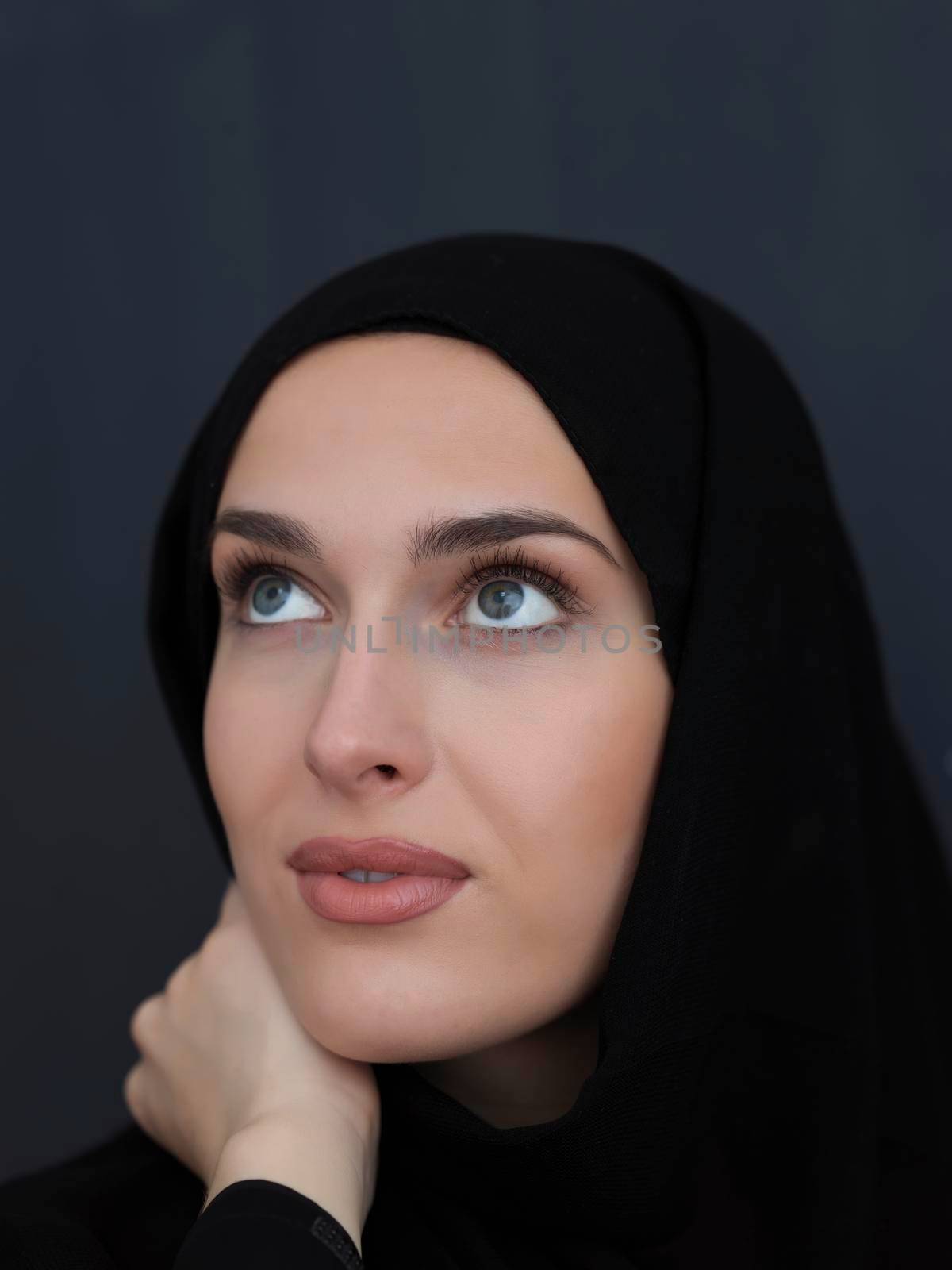 Portrait of modern young muslim woman in black abaya. Arab girl wearing traditional clothes and posing in front of black chalkboard. Representing modern and rich arabic lifestyle