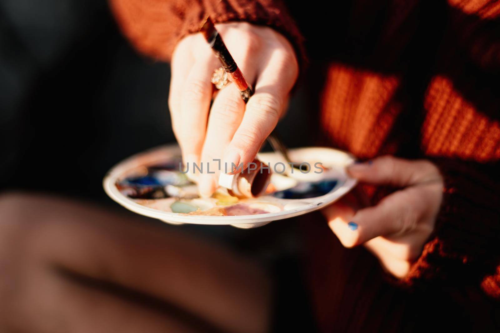 A woman's hands mixing paints on a palette board. Preparing to paint a picture. Artistic tools. The creative process