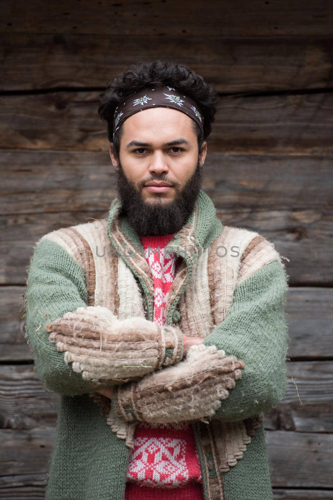 portrait of young hipster,  man with beard in front of old vintage wooden house