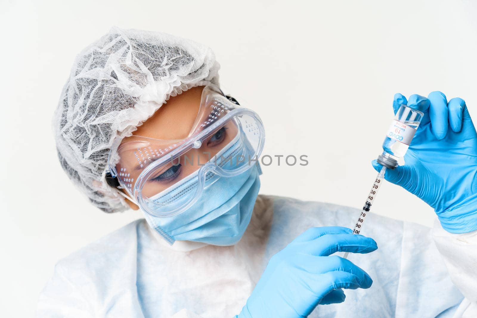 Close up portrait of asian female doctor or nurse in personal protective equipment, vaccinating from coronavirus, filling syringe with covid-19 vaccine, white background.