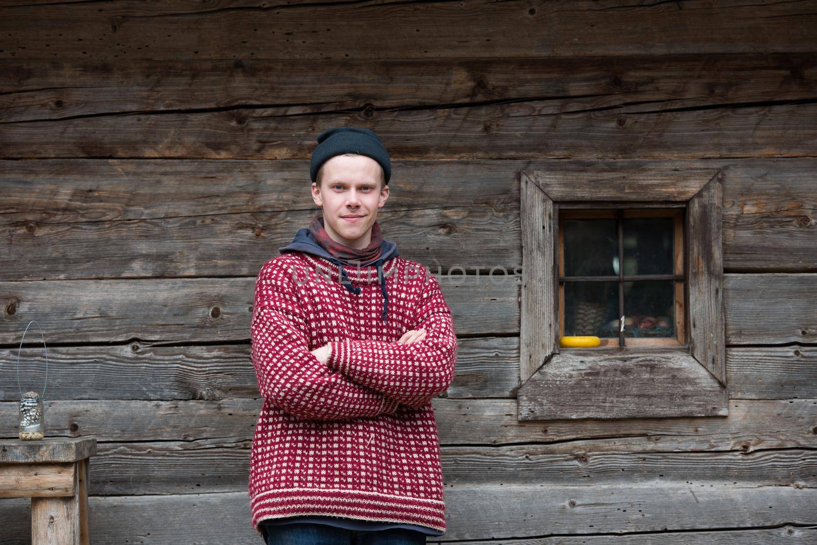 portrait of young hipster,  man with nose piercing  in front of old vintage wooden house