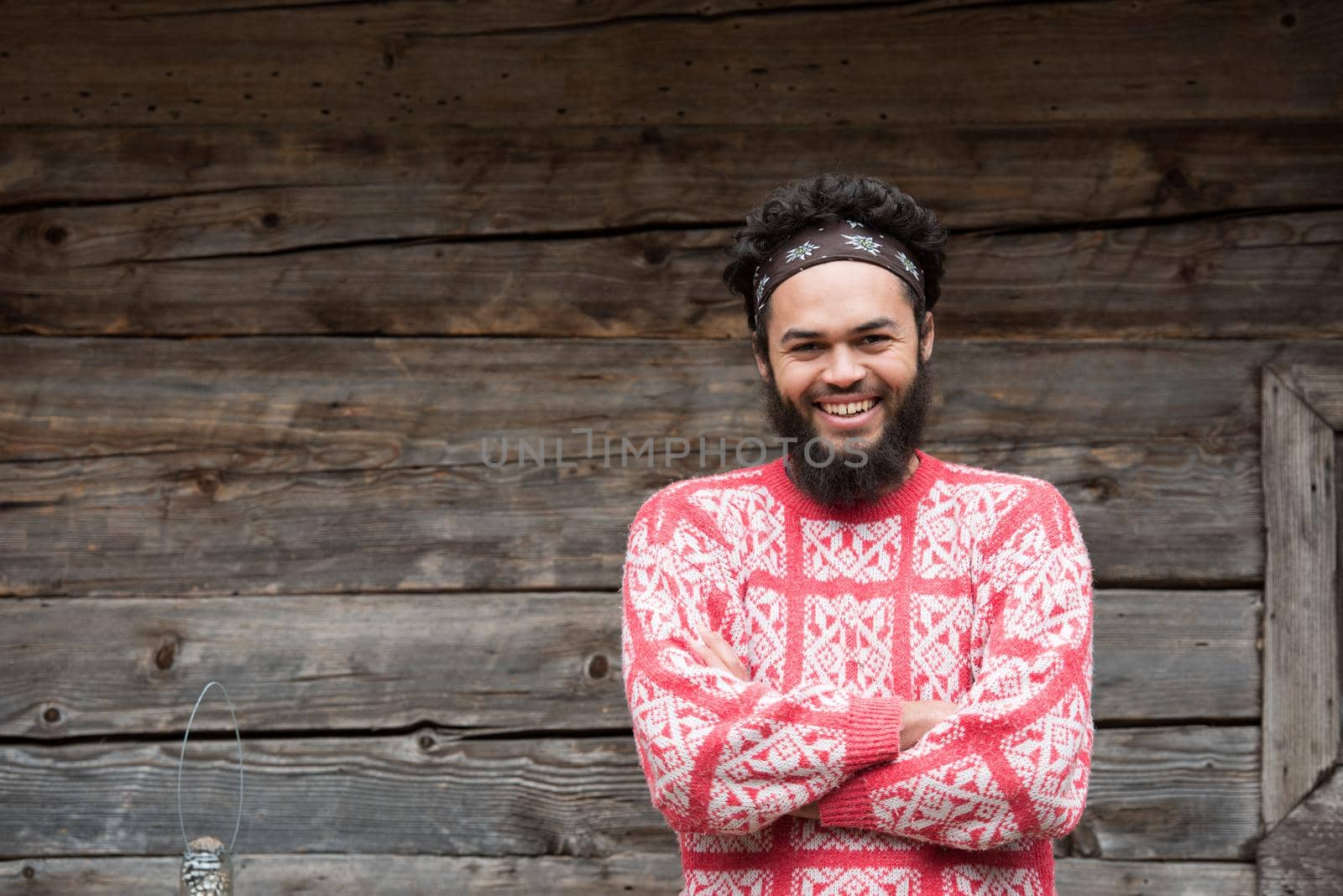 portrait of young hipster,  man with beard in front of old vintage wooden house