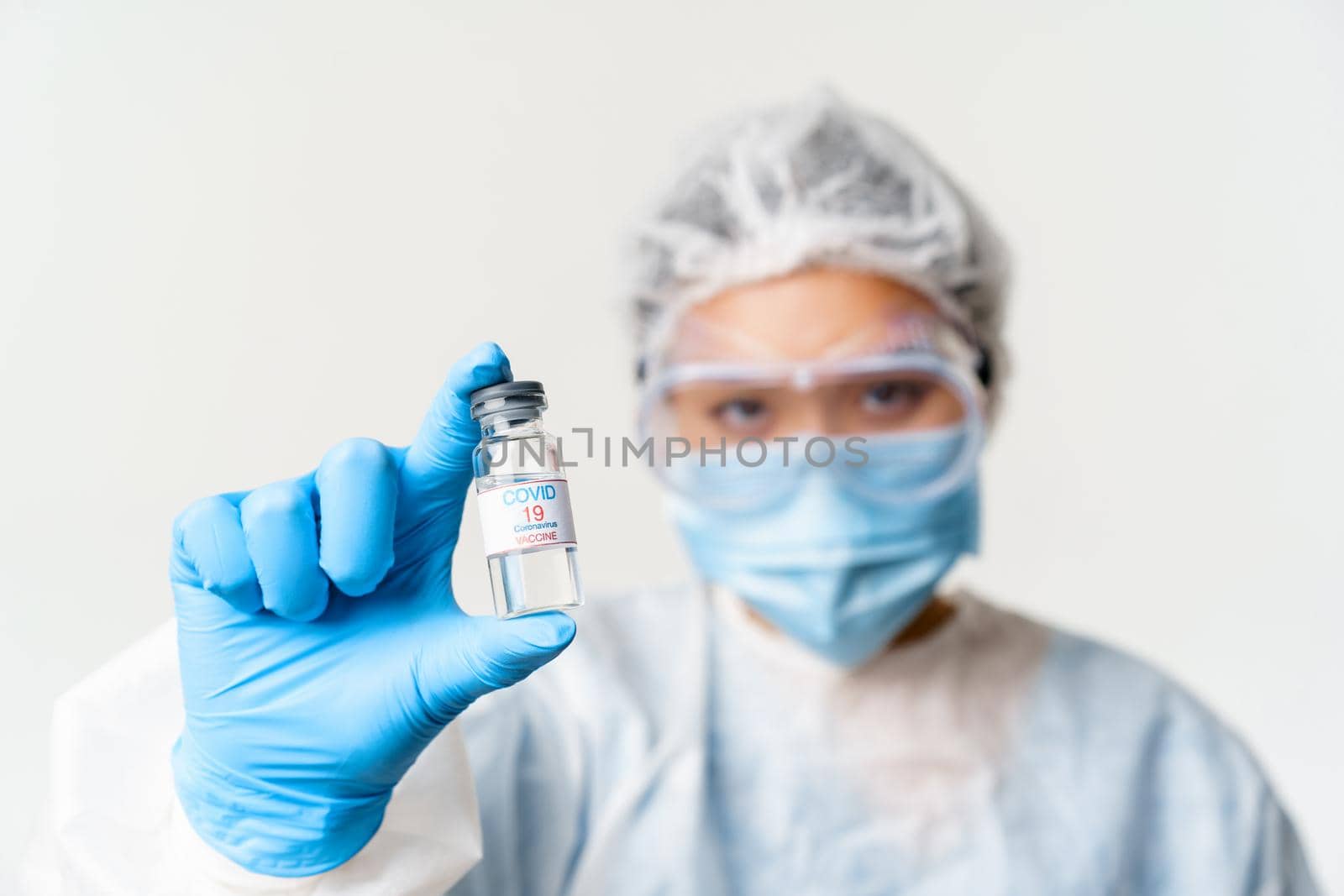 Portrait of asian doctor or nurse in personal protective equipment, female healthcare worker showing covid-19 vaccine, coronavirus vaccination concept.