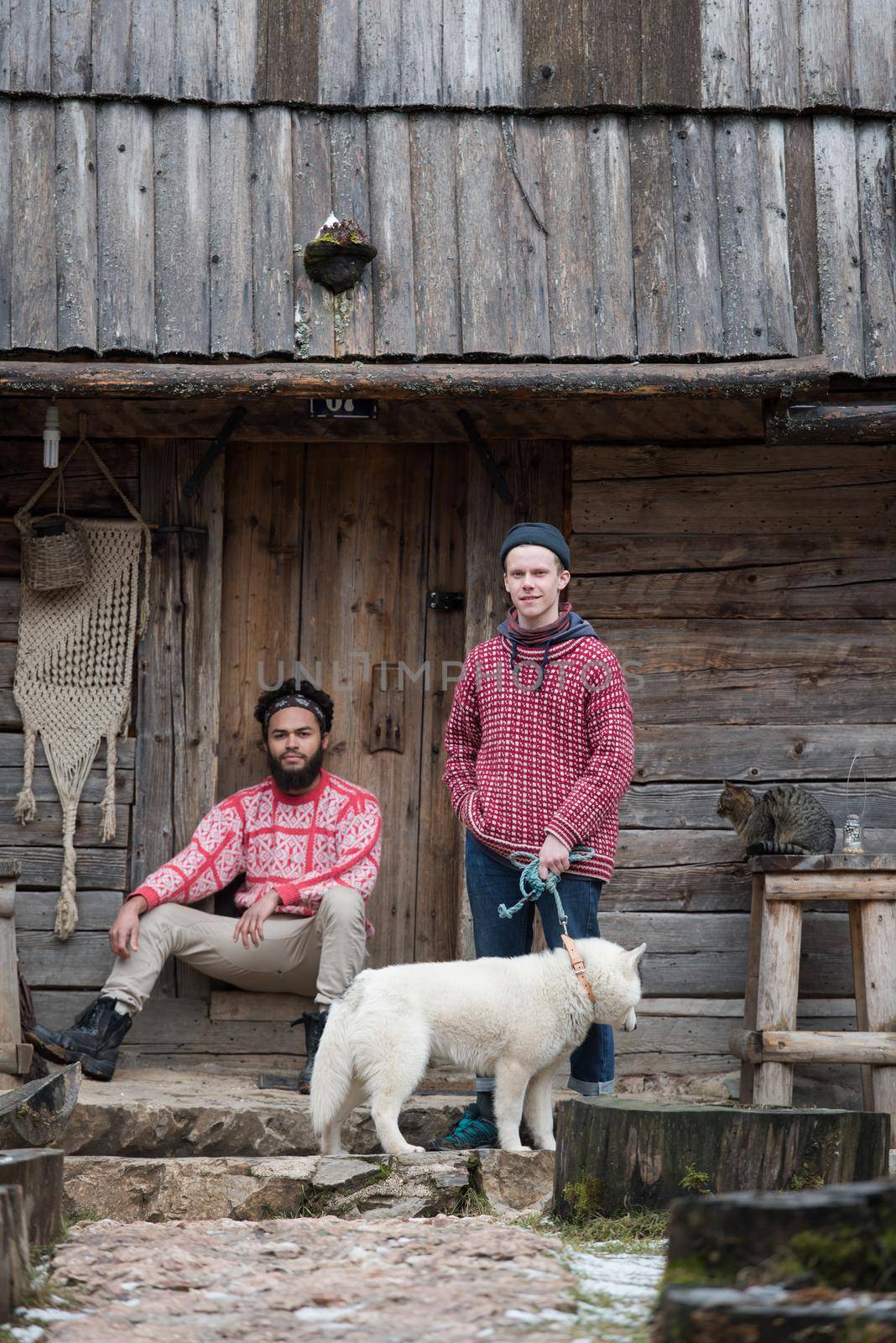 hipsters couple portrait, two young  man with white husky dog  sitting in front of old wooden retro house