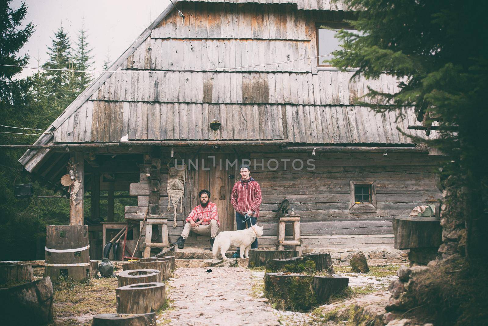 hipsters couple portrait, two young  man with white husky dog  sitting in front of old wooden retro house