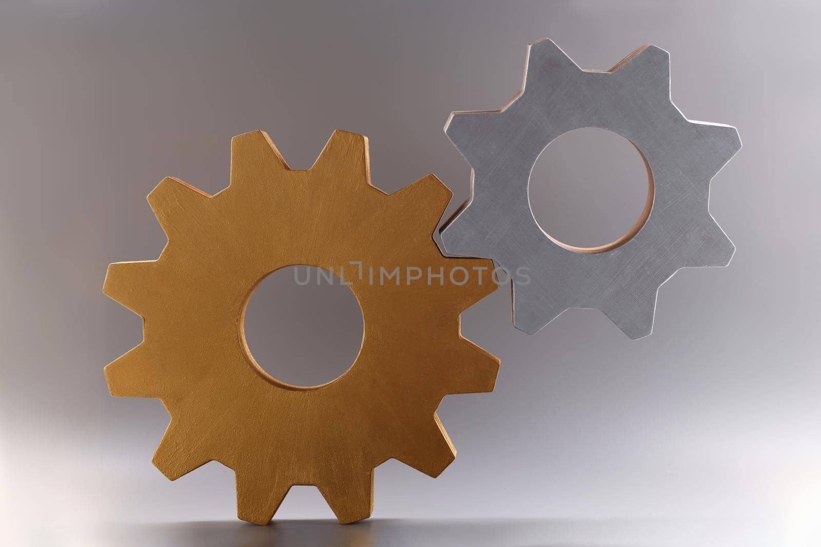 Closeup of golden and silver connected gears on gray background by kuprevich
