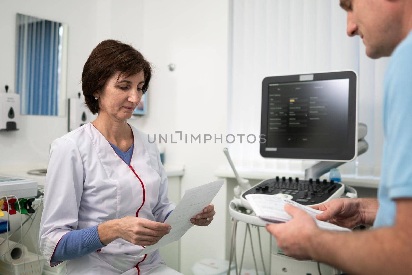 Doctor cardiologist in the office of ultrasound diagnostics with the patient examines medical tests during a health check-up in a modern clinic. Medical consultation. healthcare, medical service by Tomashevska