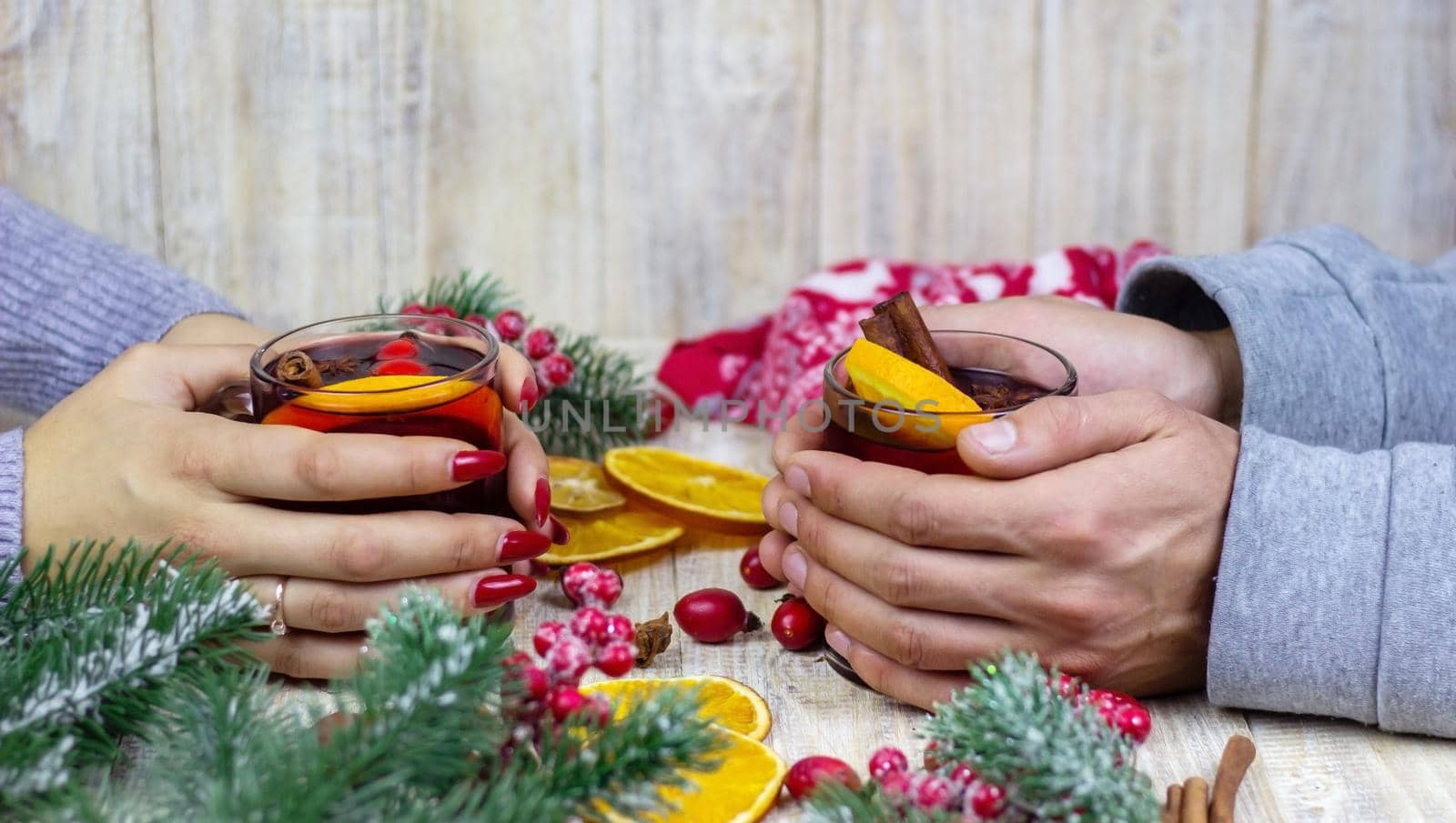 Hot mulled wine in female hands, spices on weathered wooden table. Sweet-home concept