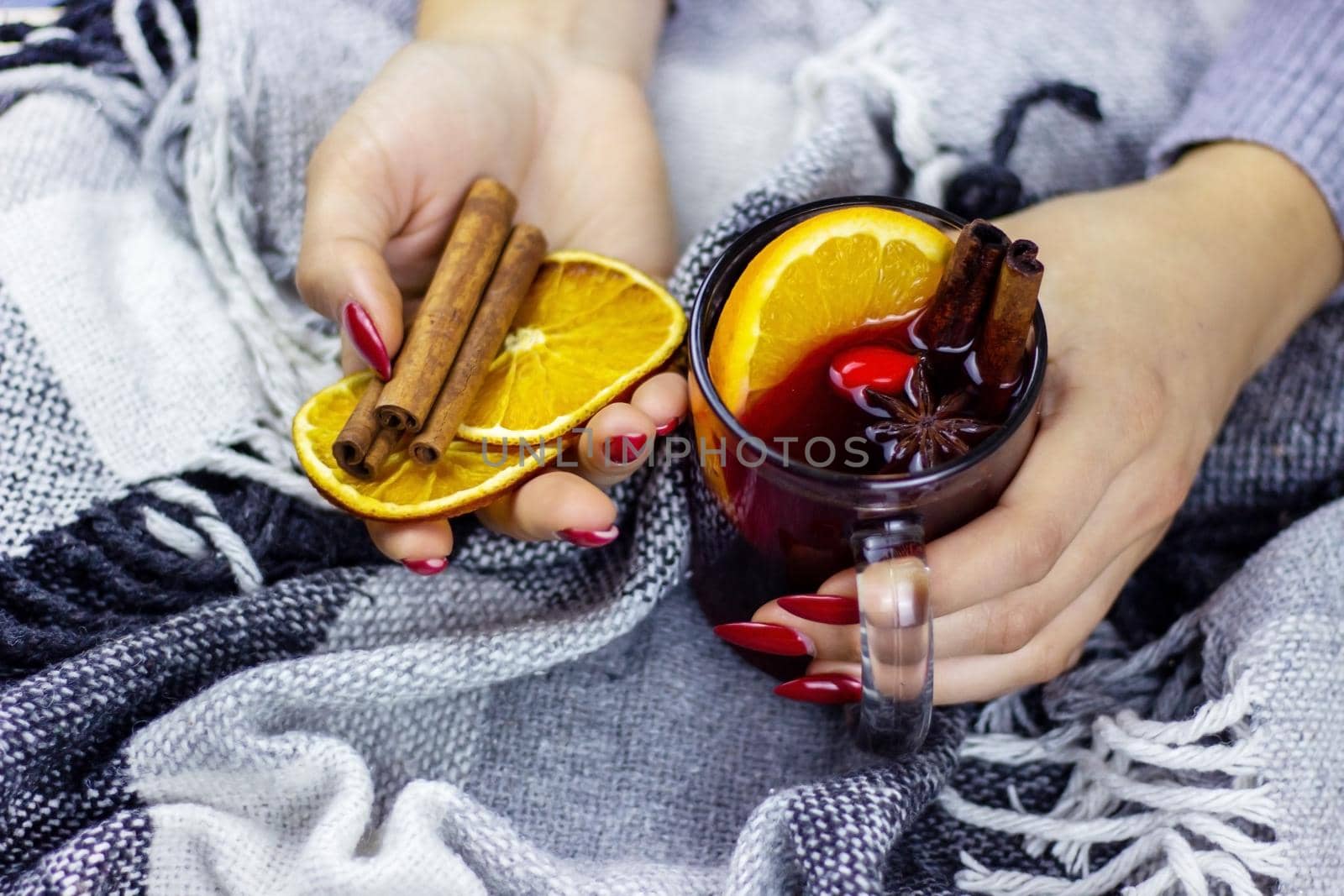 Hot mulled wine in male and female hands, spices. Sweet home concept