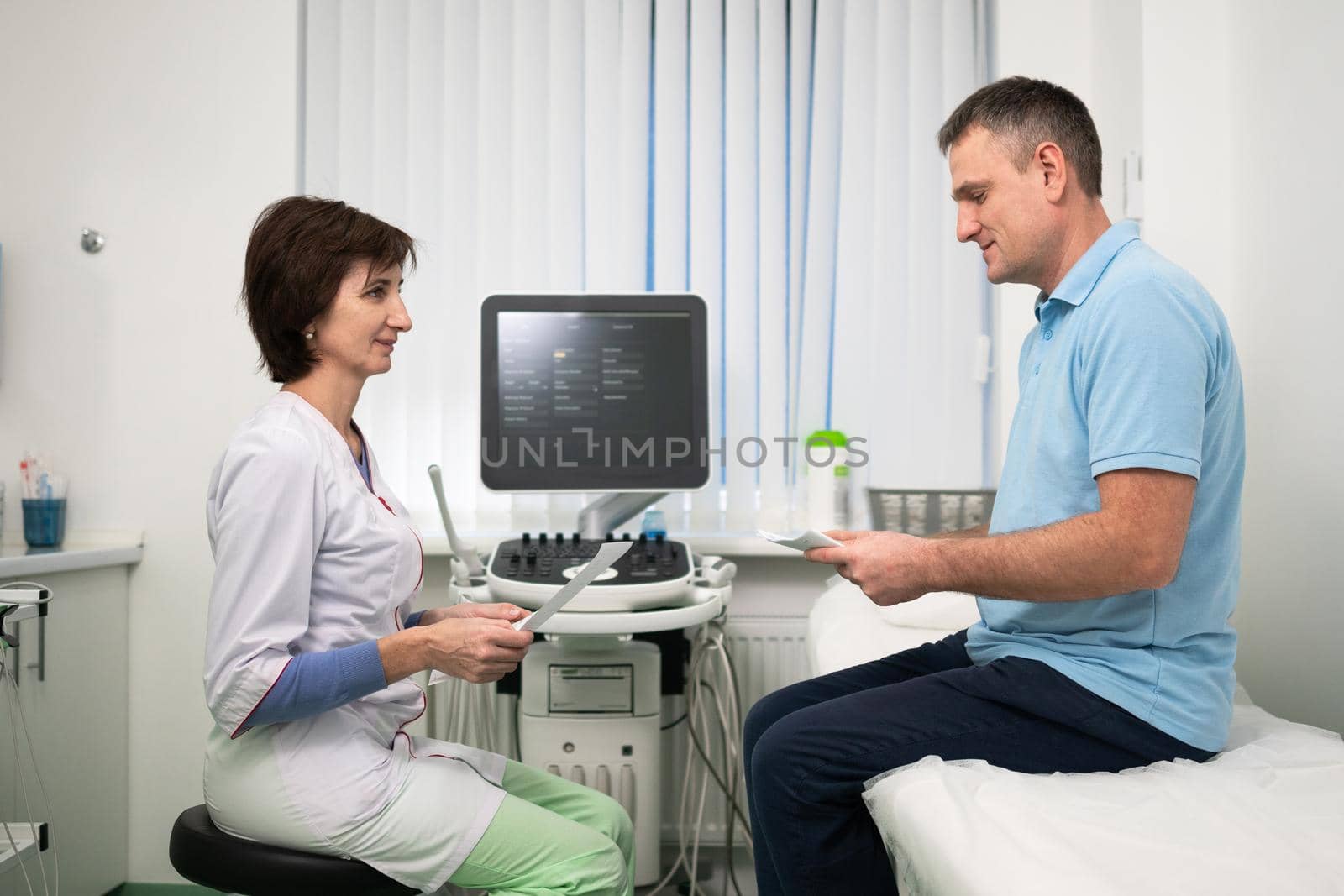 Healthcare and medicine theme. Female general practitioner will see medical tests during health examination of male patient in clinic office. Medical worker in ultrasound diagnostic room with patient.
