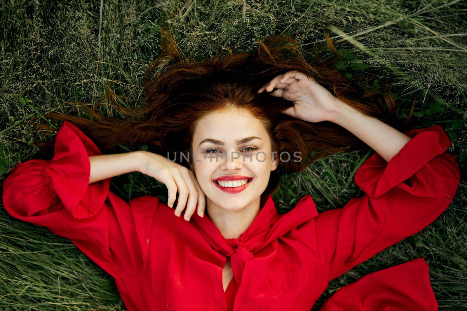 woman in a red dress lies on the grass fashion nature summer. High quality photo
