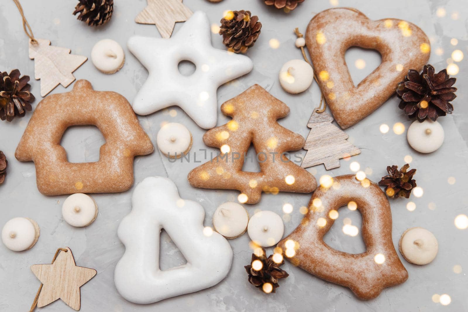 Banner for Christmas and New Year gingerbread stars, houses, Christmas trees, toys on a gray concrete background, Christmas lights bokeh in the foreground.