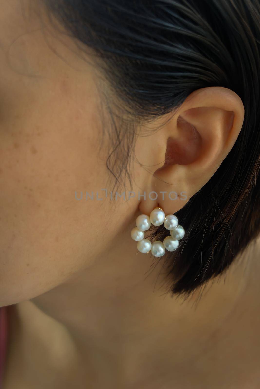 Detail of young woman wearing beautiful white pearl earring.  by tosirikul