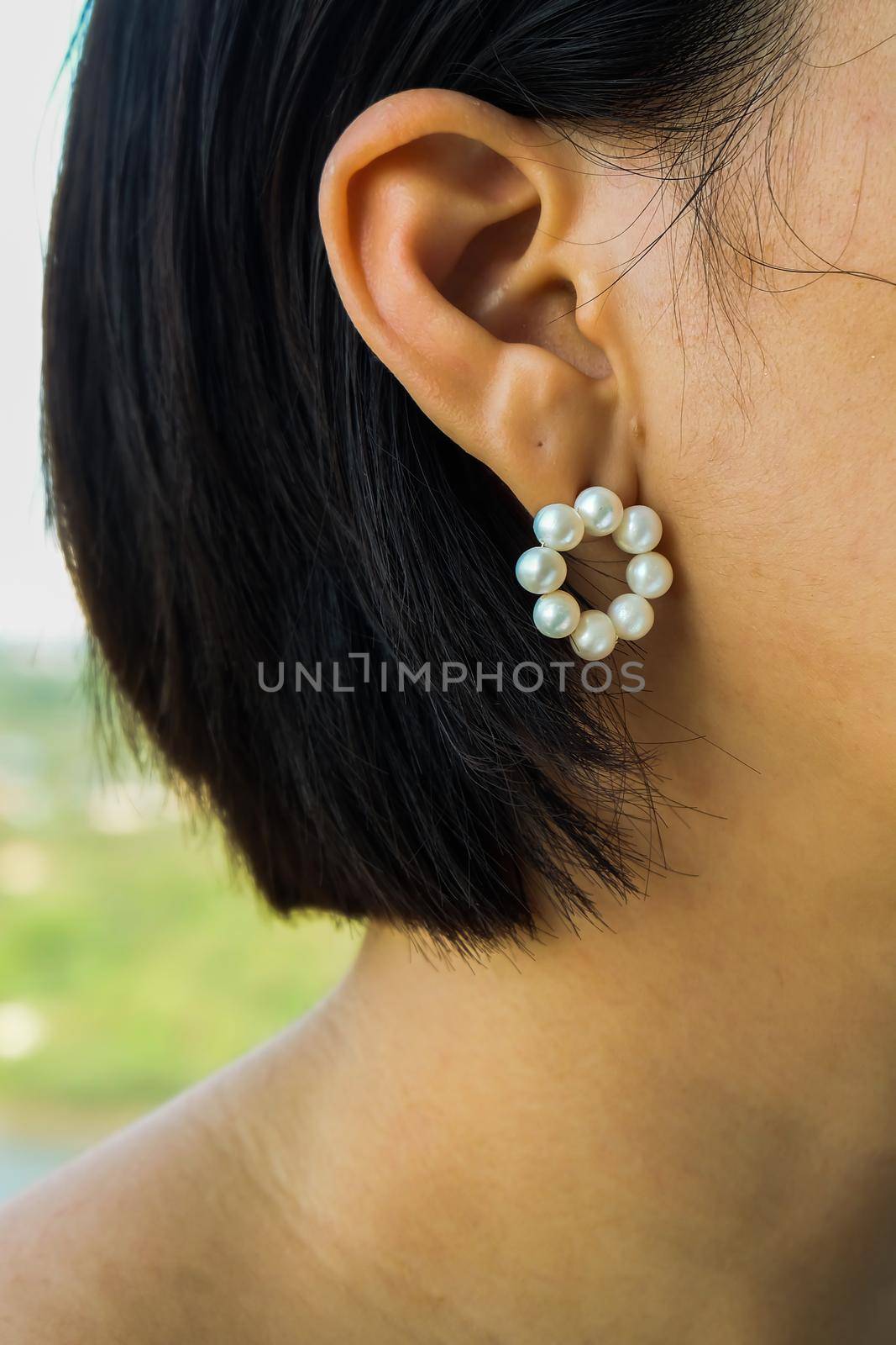 Detail of young woman wearing beautiful white pearl earring. Women accessories. Selective focus.