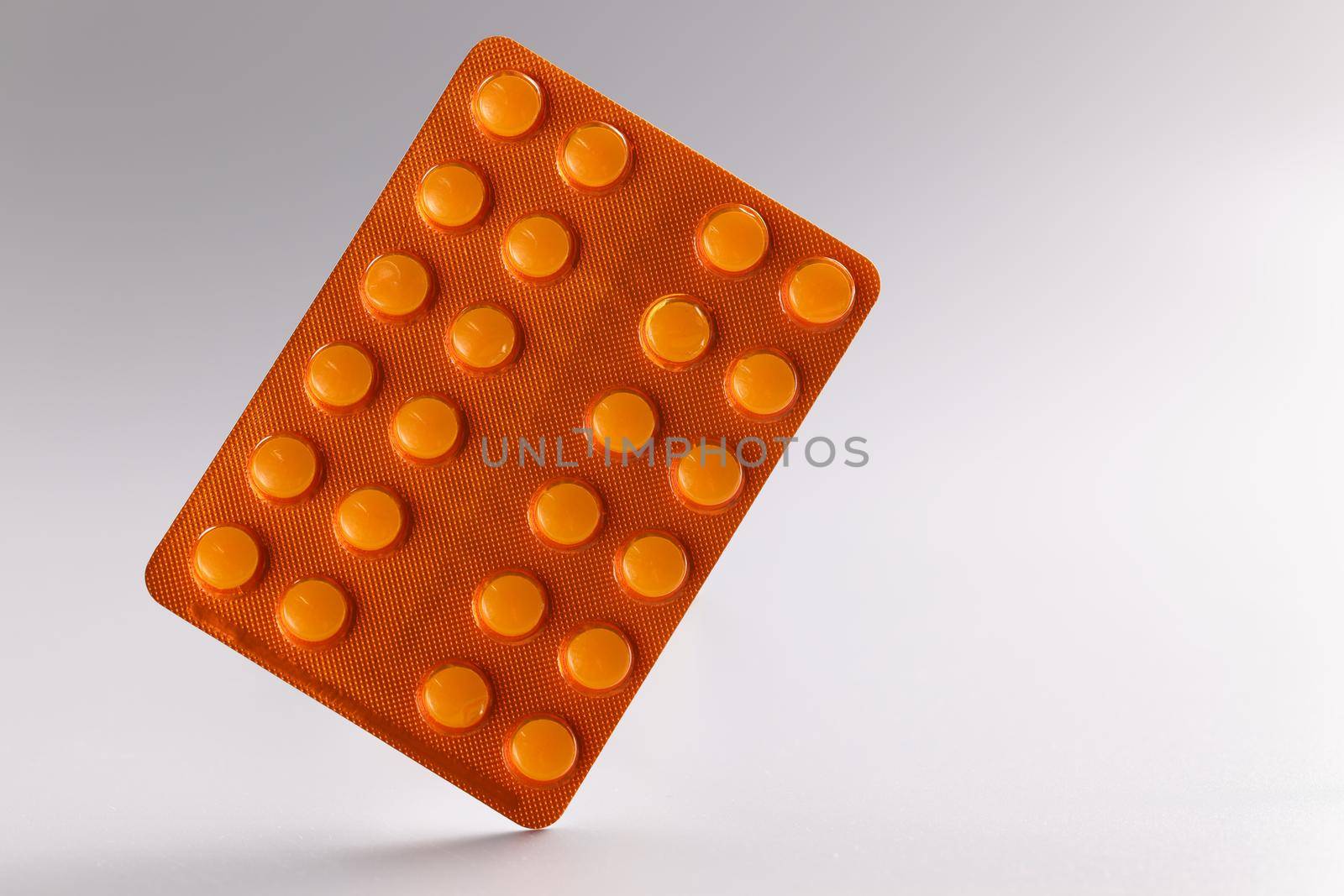 Orange blister with pills on gray background. by kuprevich