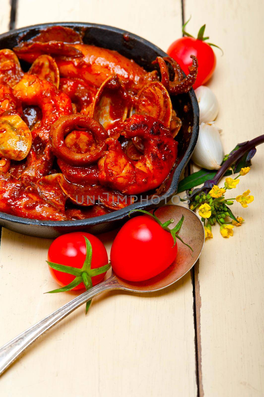 fresh seafood stew prepared on an iron skillet ove white rustic wood table 