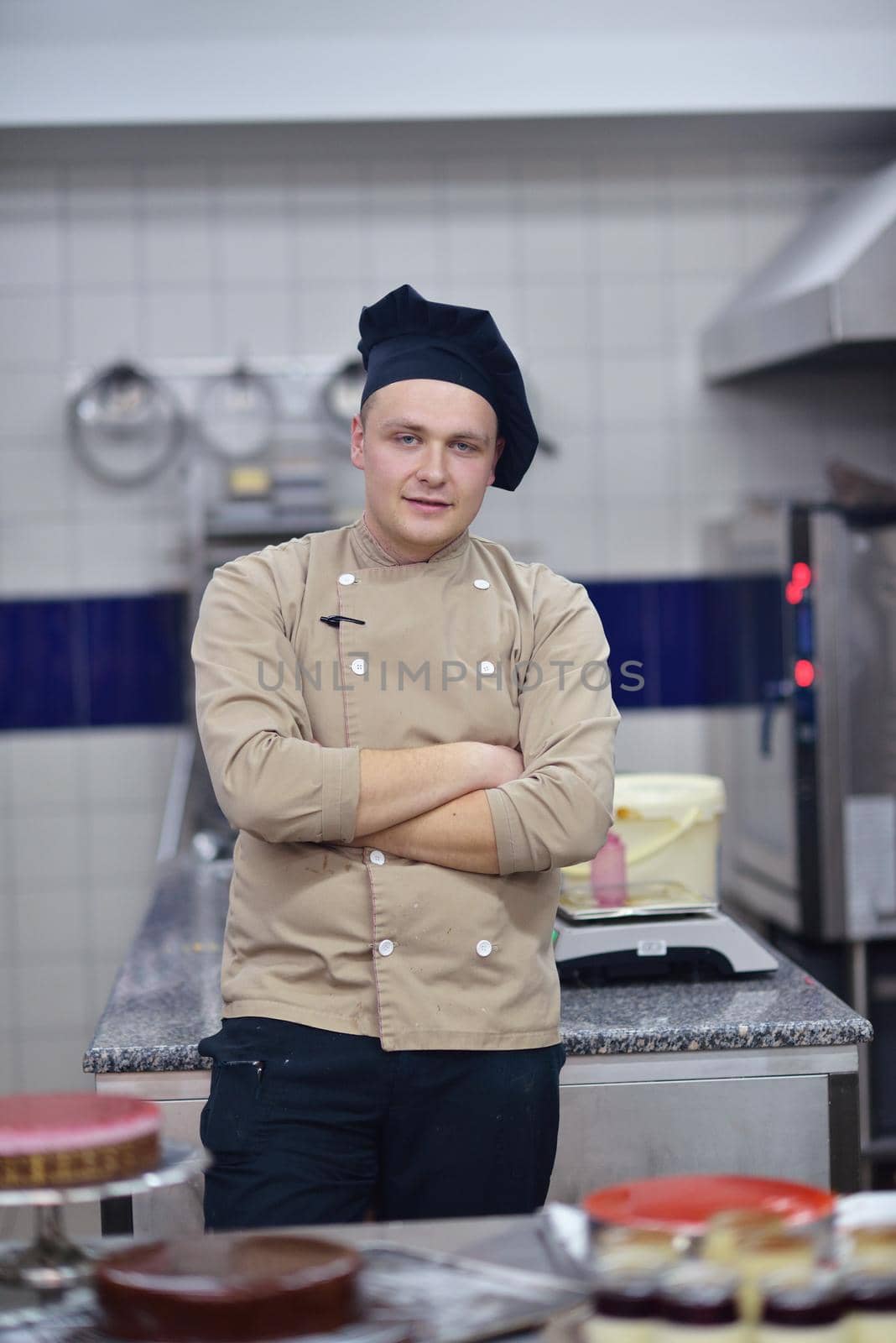 Closeup of a concentrated male pastry chef decorating dessert cake food in the kitchen