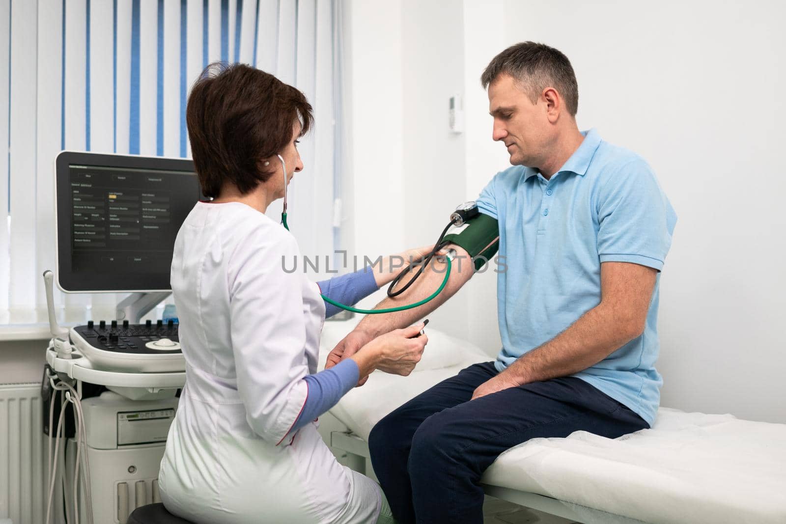 Female doctor measures blood pressure with a sphygmomanometer to male patient at medical examination in clinic office. Cardiologist checks blood pressure of male patient at cardiology hospital.