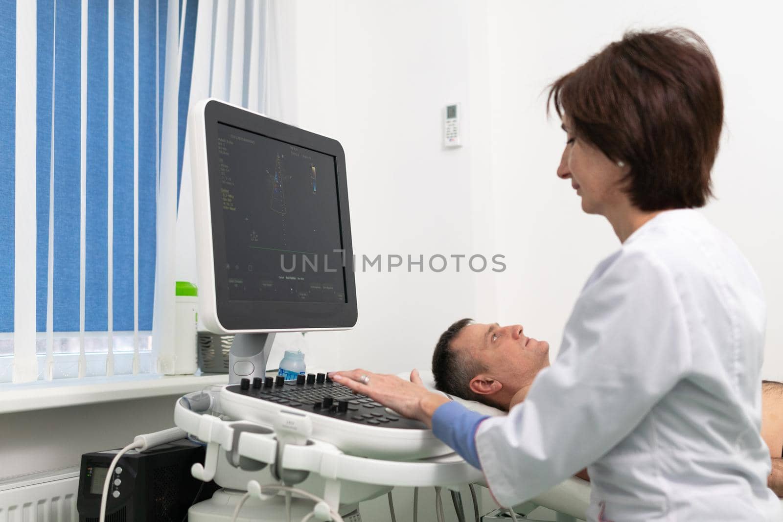 Doctor doing a doppler sonography a male patient in a cardiology clinic. Cardiologist performing an ultrasound examination at the cardiovascular hospital. Echocardiography procedure by Tomashevska