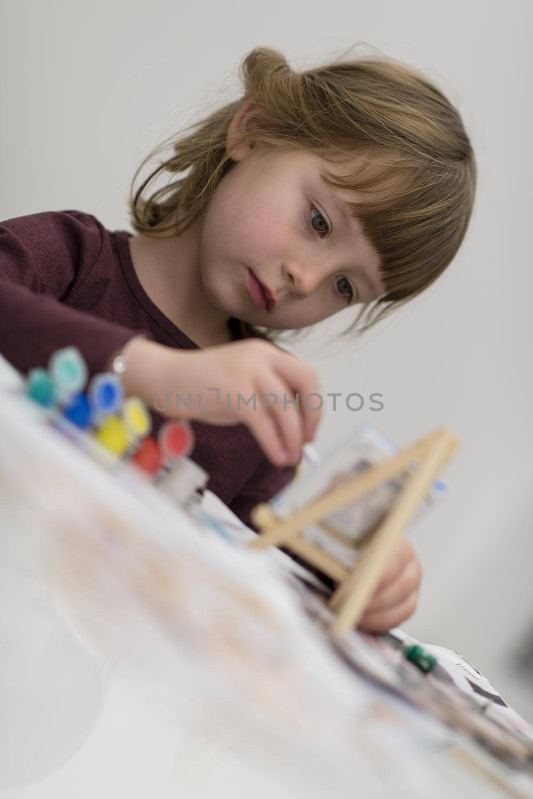 happy little girl painting on canvas image at home