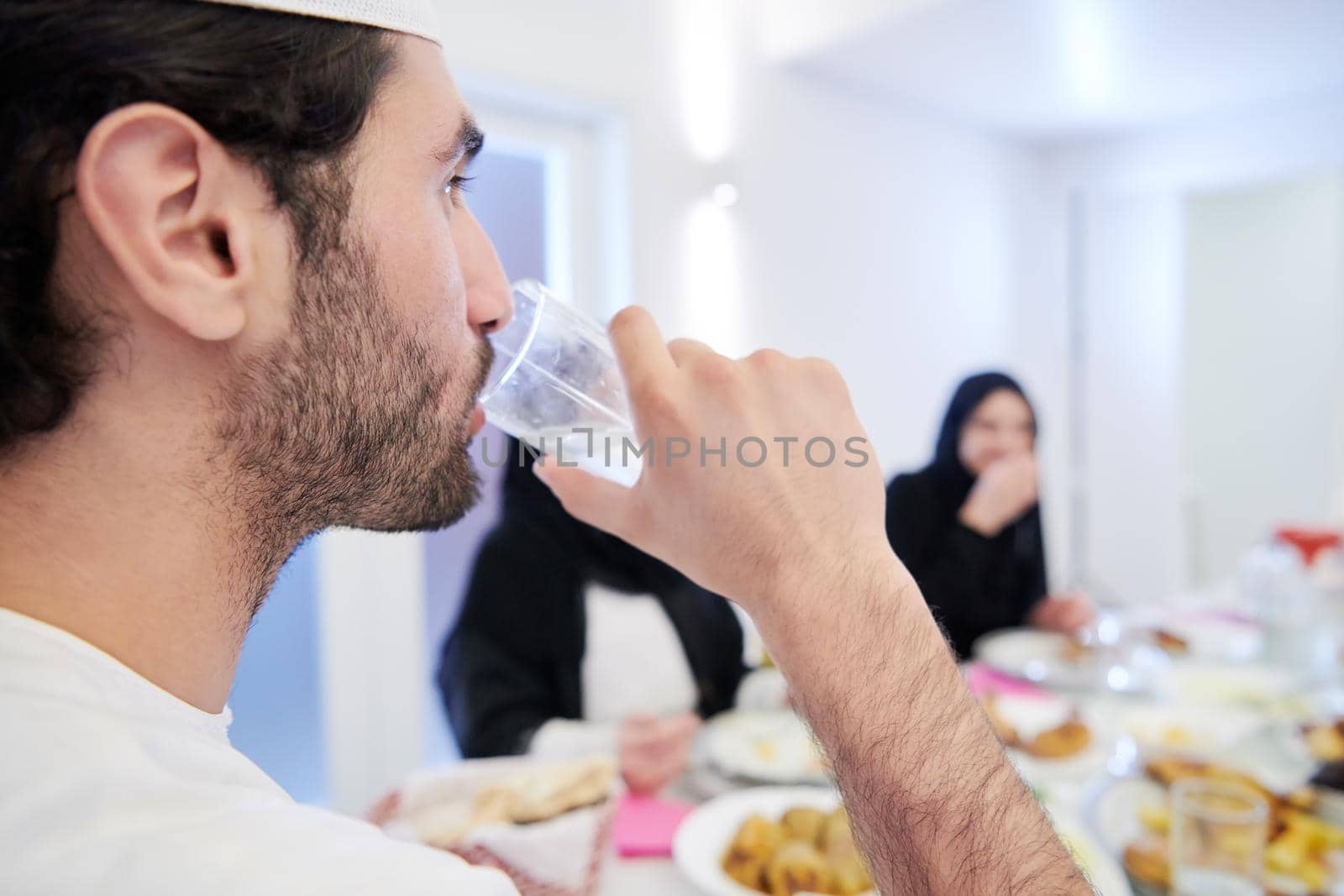 Muslim family having Iftar dinner drinking water to break feast by dotshock