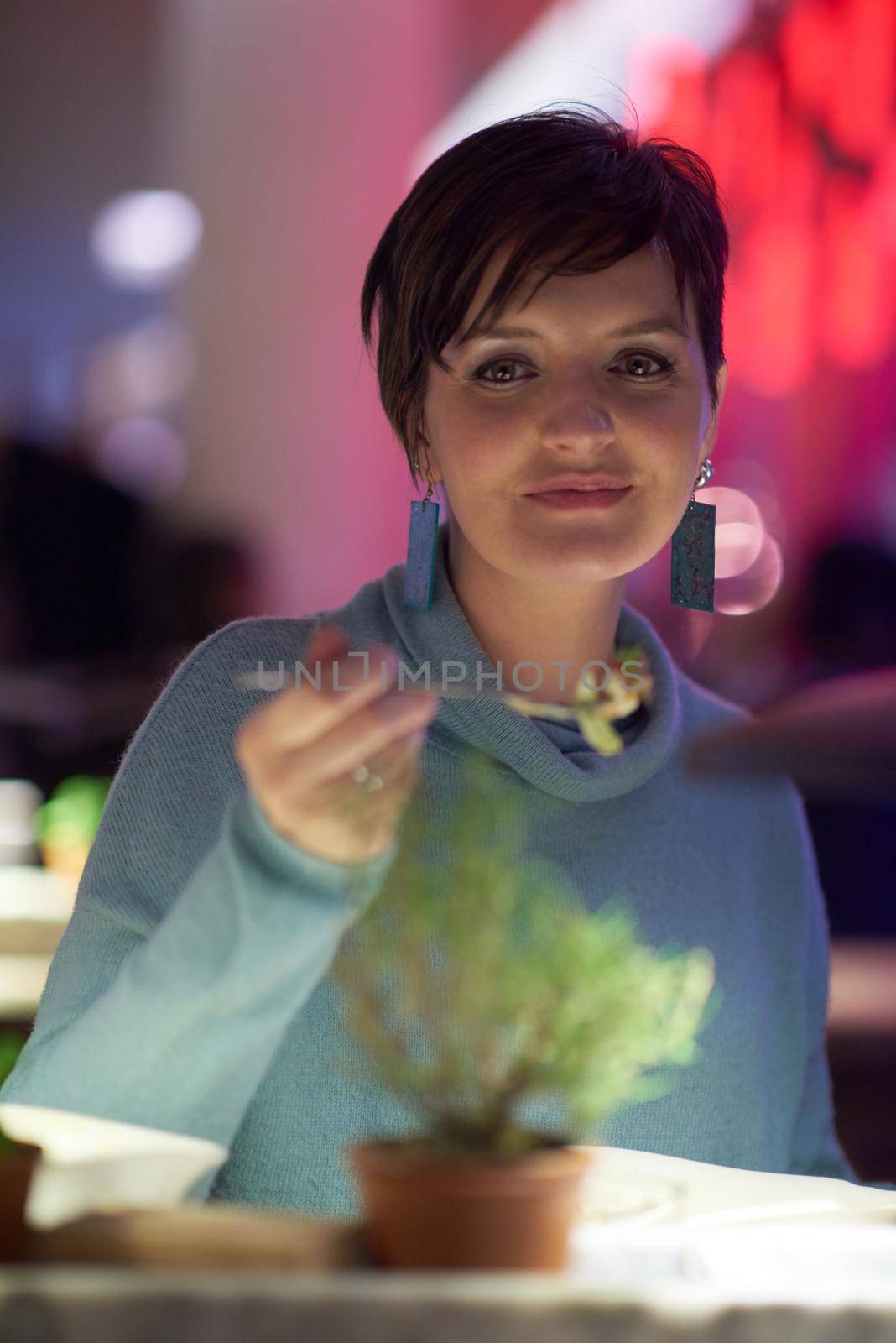 woman portrait eating tasty  dinner in modern restaurant at night