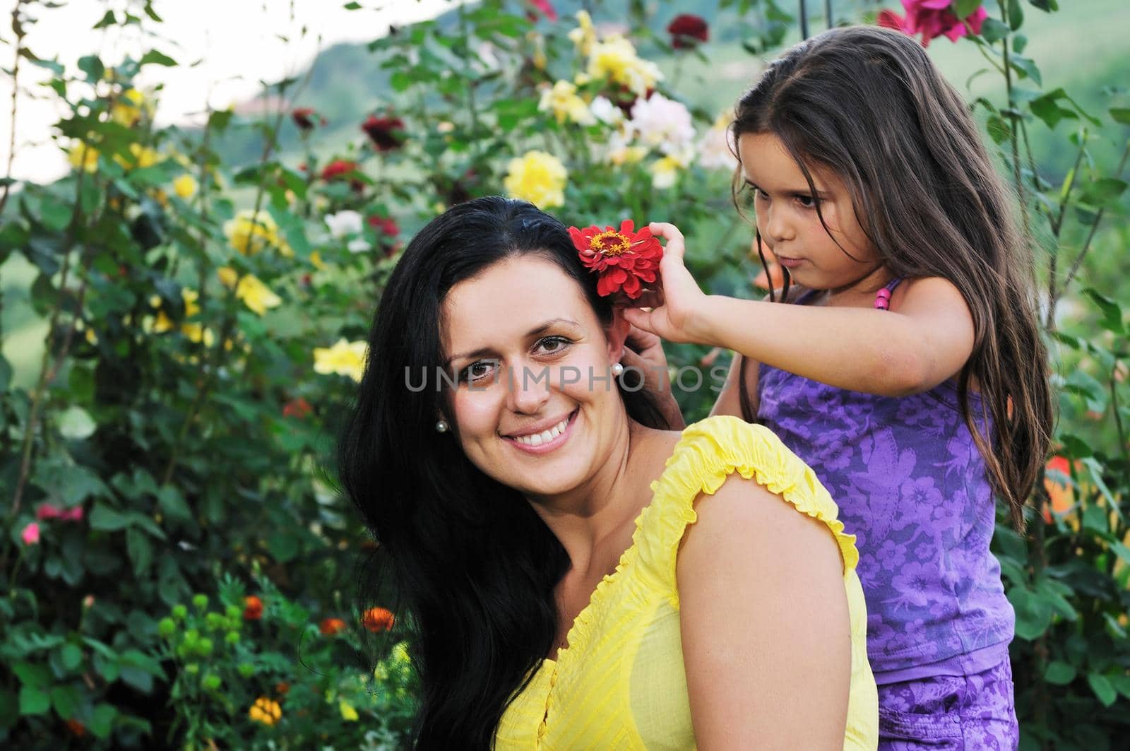 beautiful mom and daughter outdoor in garden  together with flower have fun and hug 