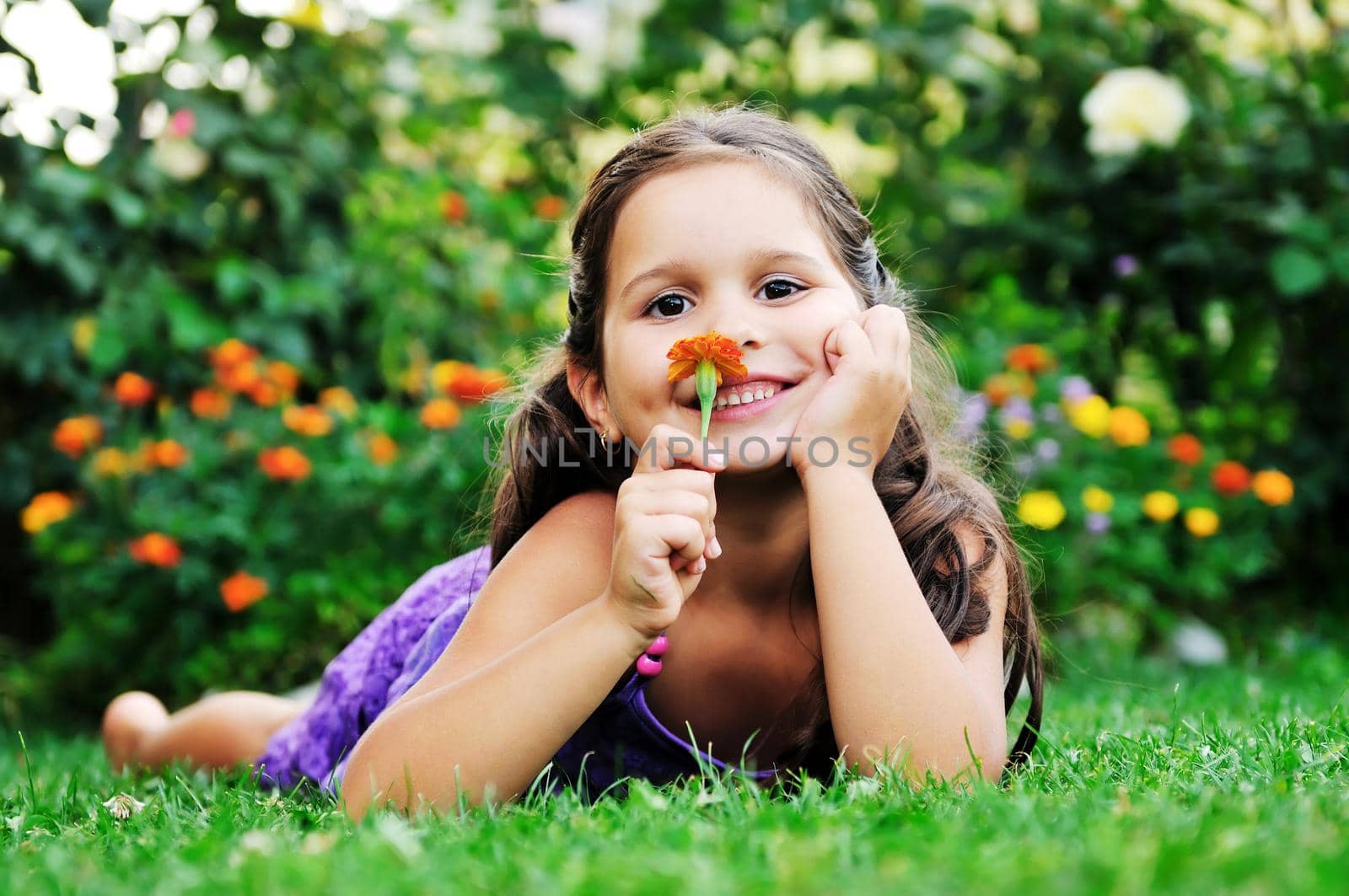 happy young girl children relax lie and have fun on grass with flower