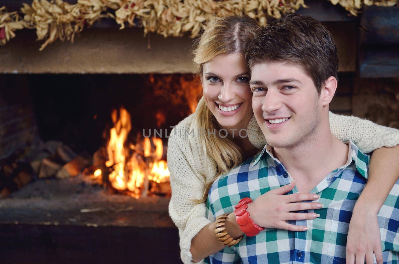 Young romantic couple sitting and relaxing in front of fireplace at home by dotshock