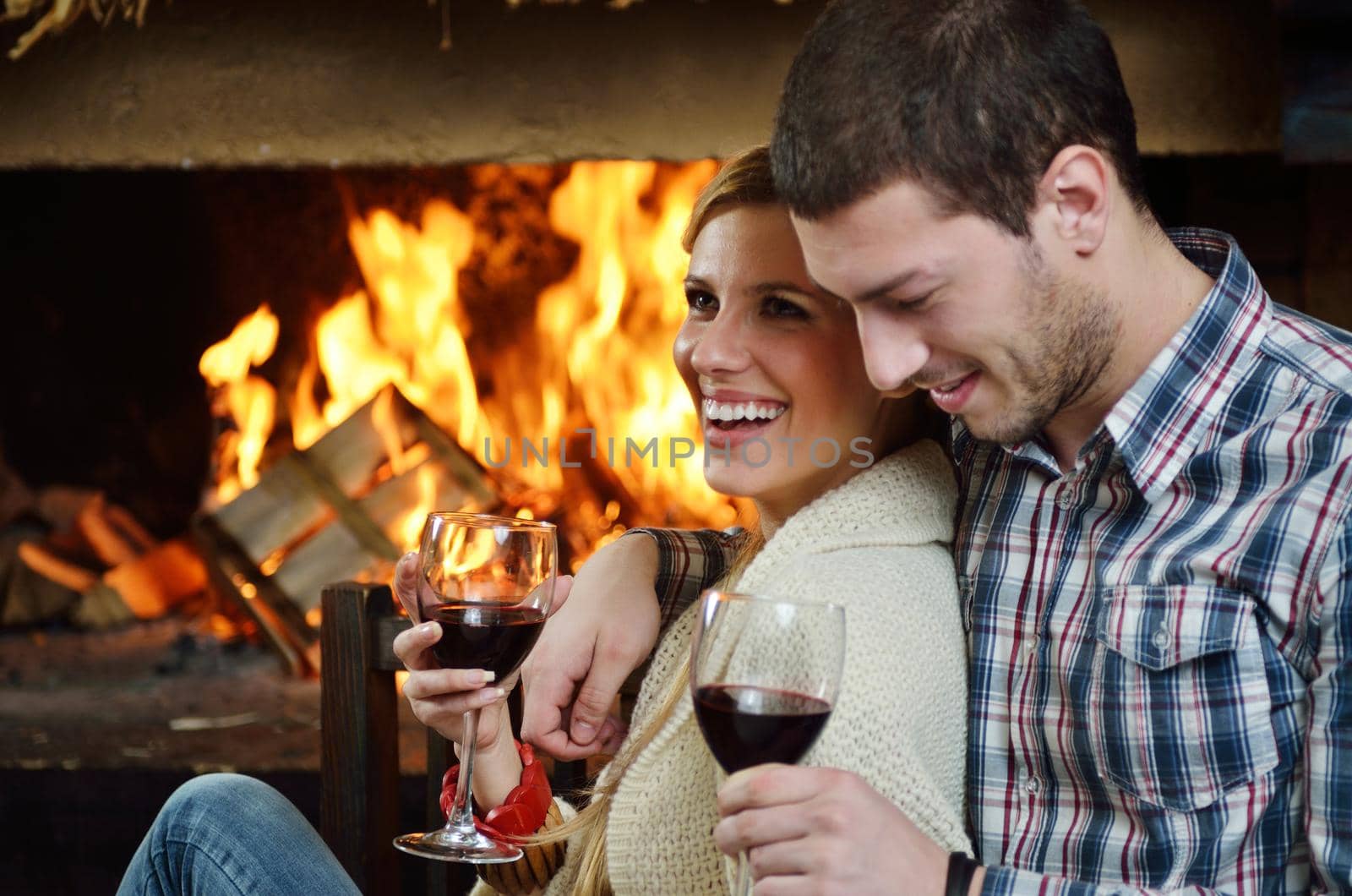 happy Young romantic couple sitting on sofa in front of fireplace at winter season in home