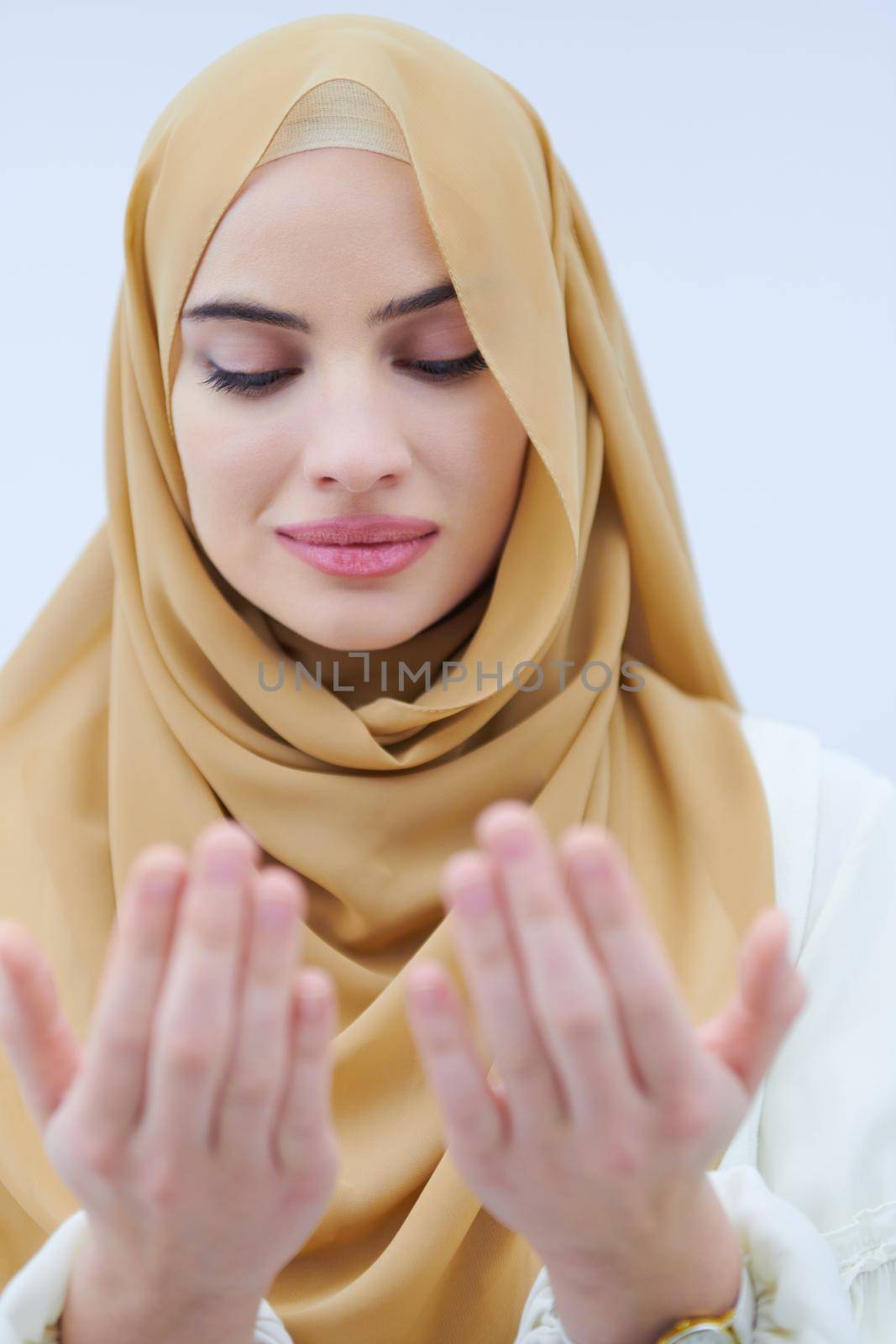 beautiful muslim woman in fashionable dress with hijab making traditional prayer to God, keeps hands in praying gesture isolated on white background representing modern islam fashion and ramadan kareem concept