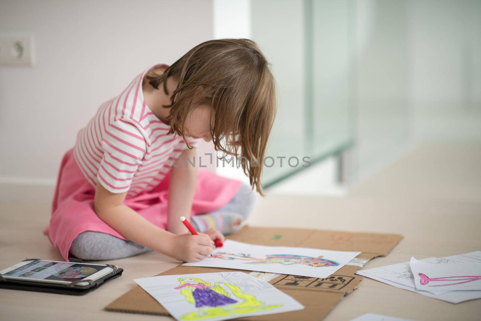 child playign at home while drawing colorful art and looking digital tablet