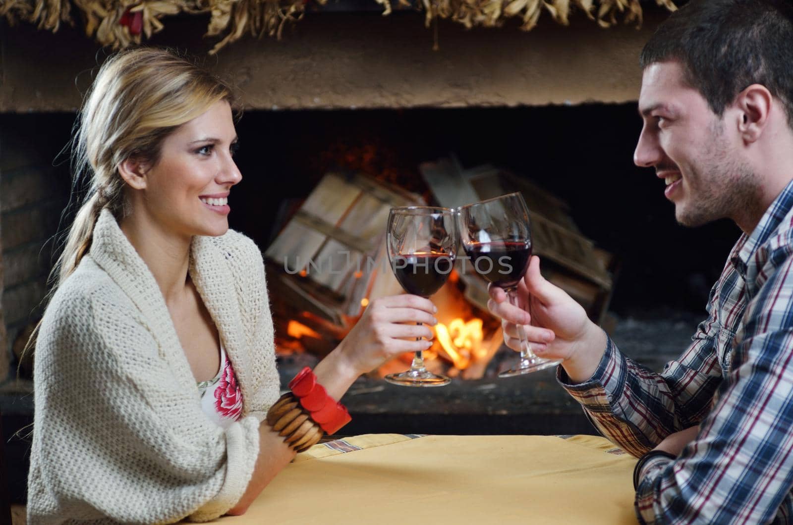 happy Young romantic couple sitting on sofa in front of fireplace at winter season in home