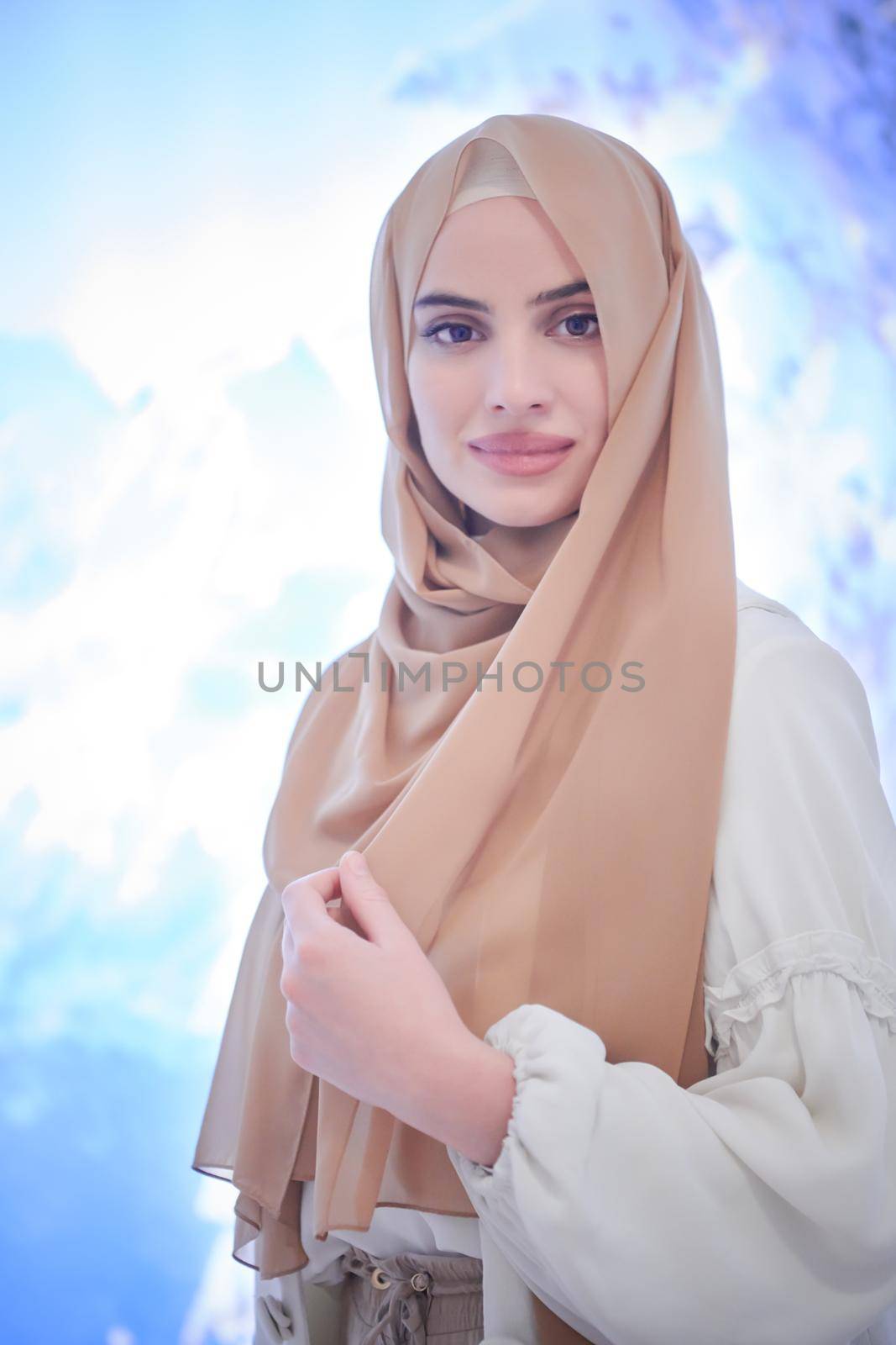 portrait of beautiful muslim woman in fashionable dress with hijab isolated on modern winter mountains background representing modern islam fashion and ramadan kareem concept