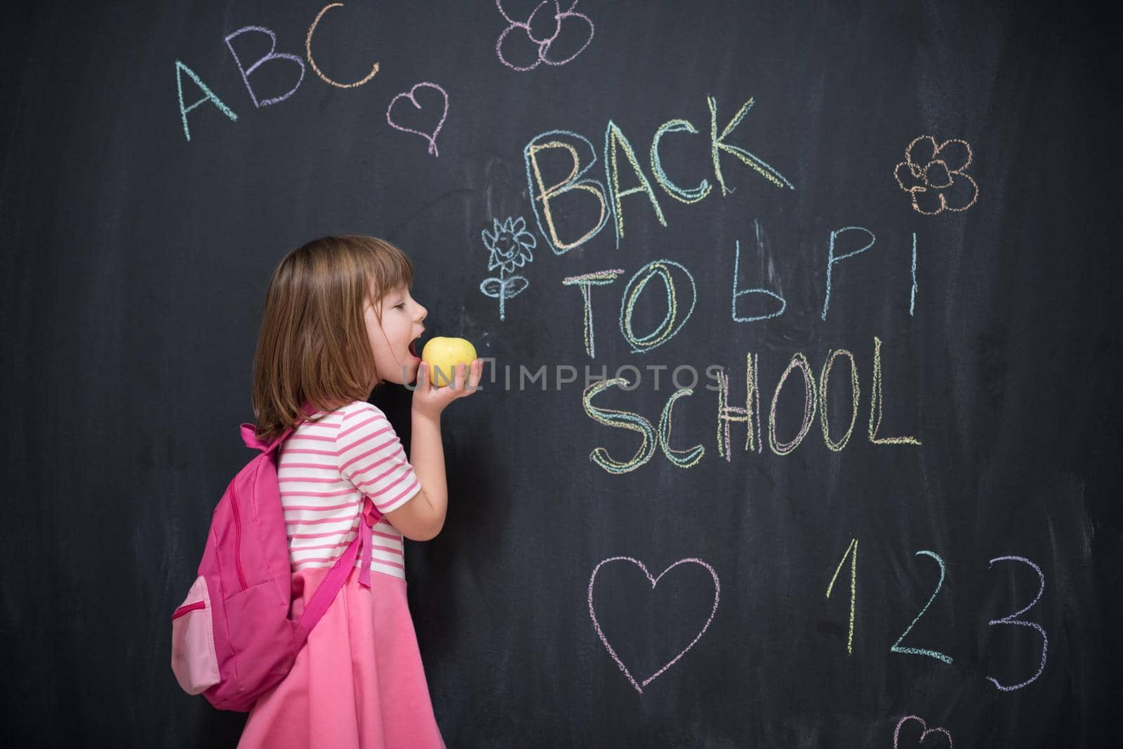 happy child with apple and back to school drawing in background on black chalkboard
