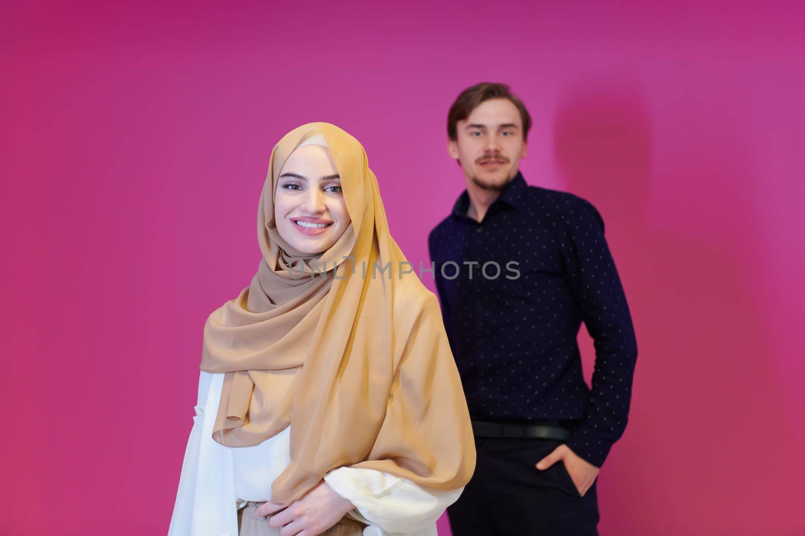 portrait of young muslim couple woman in fashionable dress with hijab isolated on pink background representing modern islam fashion and ramadan kareem concept