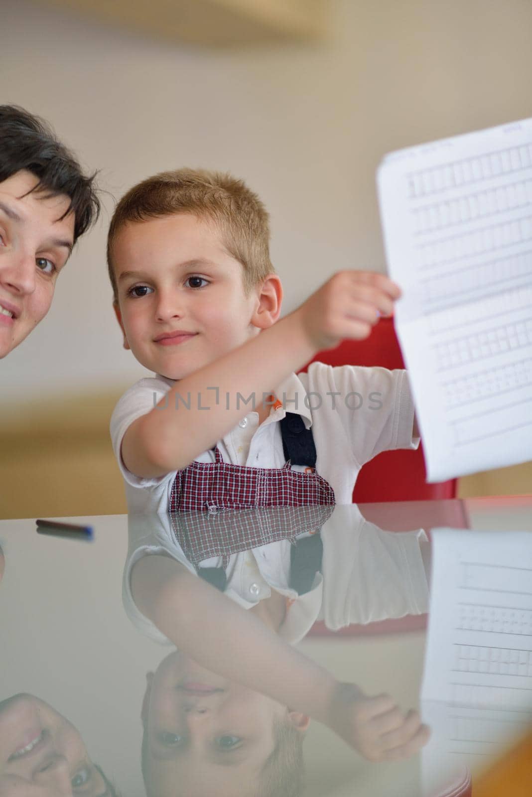 young mom woman doing home work with elementary school grade boy at home in kitchen