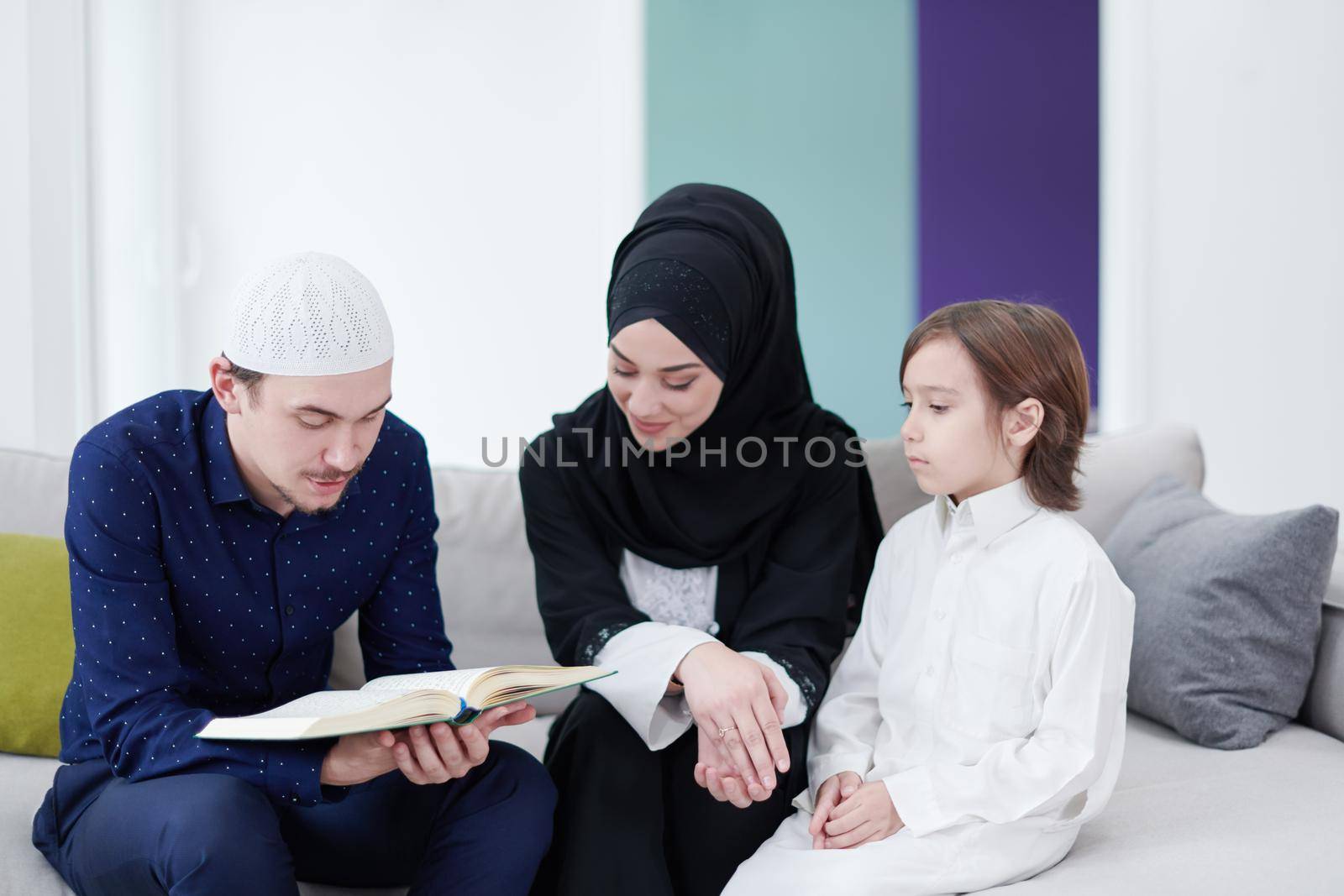 muslim family reading Quran and praying at home by dotshock