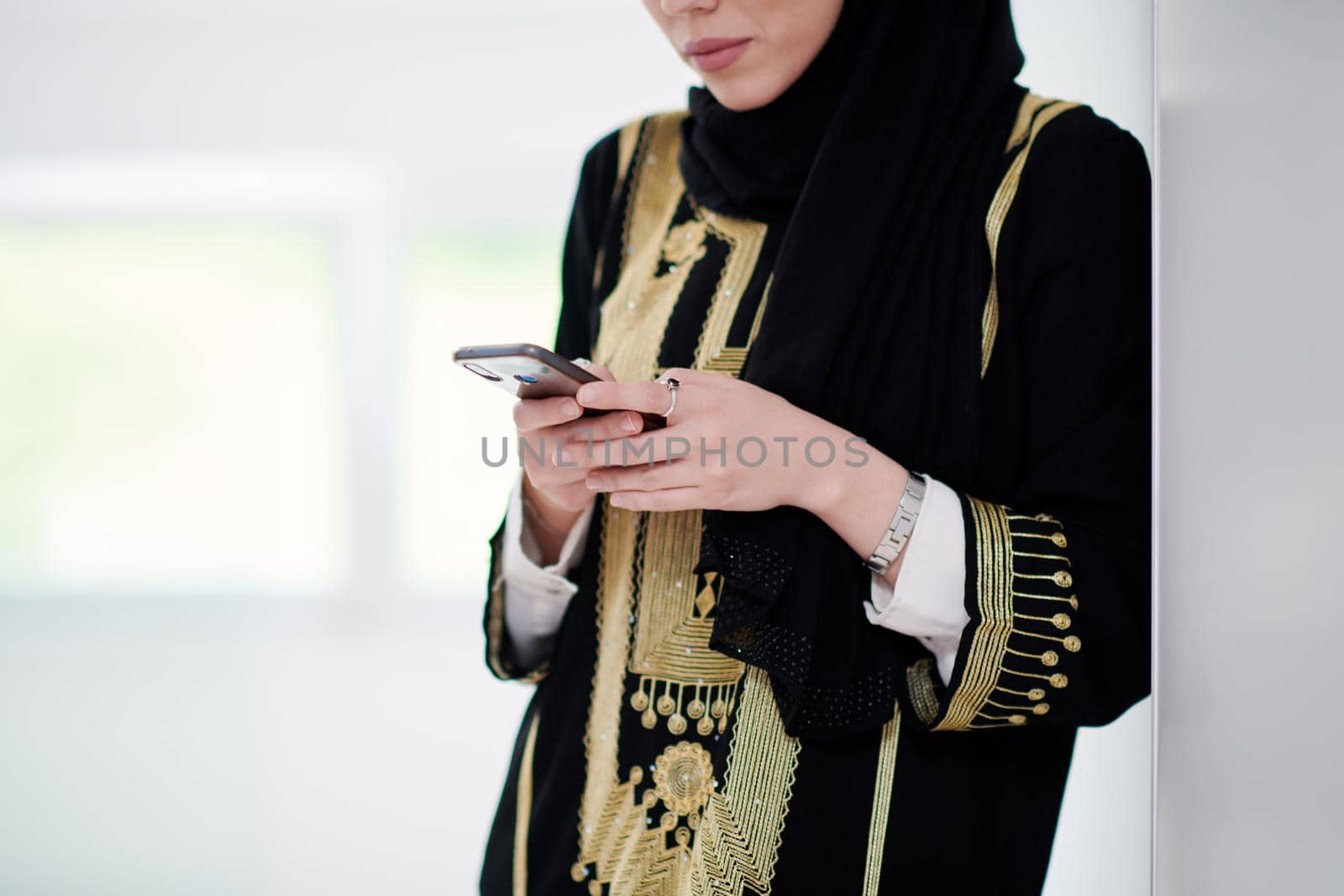 young modern muslim business woman using smartphone at home by dotshock