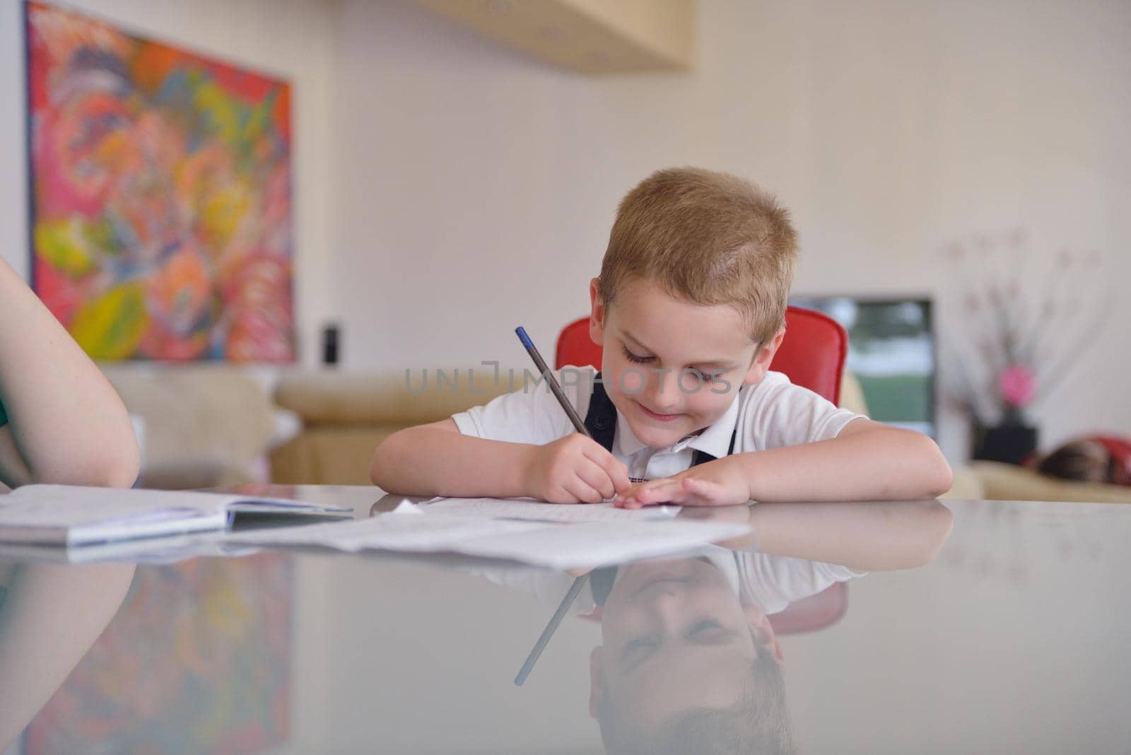 young mom woman doing home work with elementary school grade boy at home in kitchen