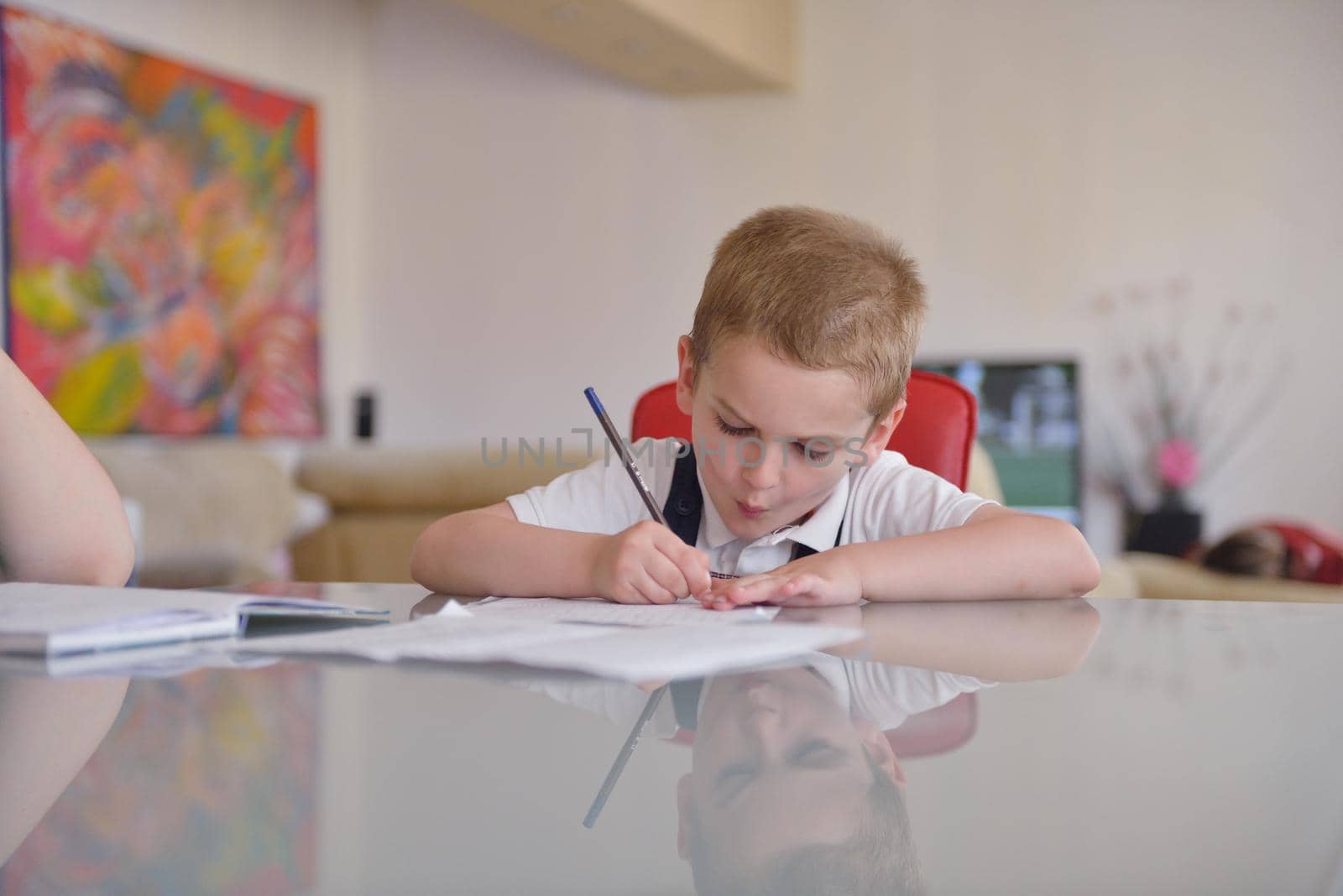 young mom woman doing home work with elementary school grade boy at home in kitchen