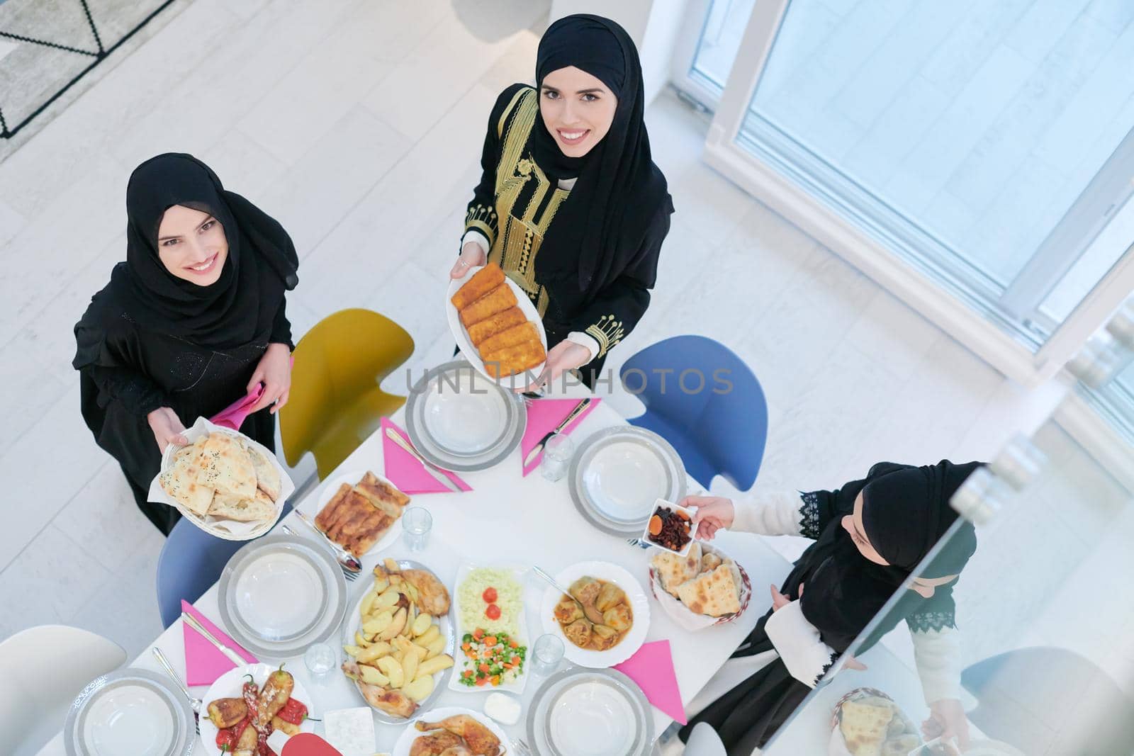 Eid Mubarak Muslim family having Iftar dinner  young muslim girls serving food on the table during Ramadan feasting month at home. The Islamic Halal Eating and Drinking Islamic family top view