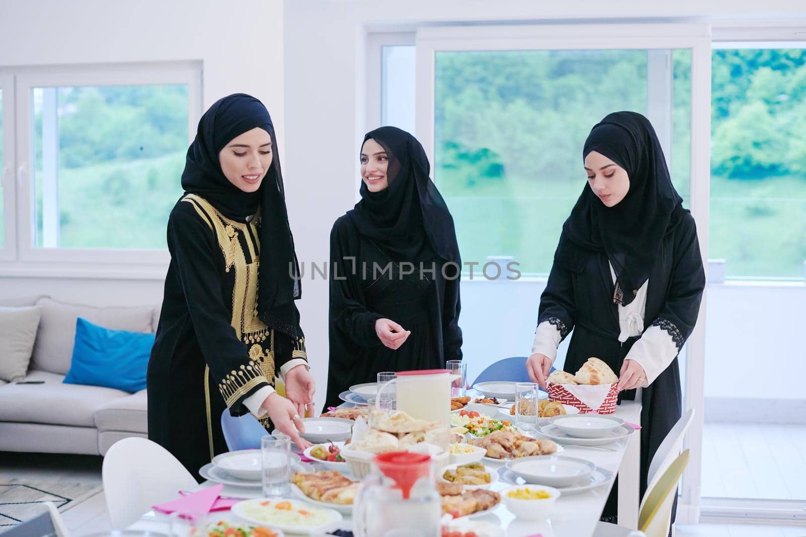 Eid Mubarak Muslim family having Iftar dinner  young muslim girls serving food on the table during Ramadan feasting month at home. The Islamic Halal Eating and Drinking Islamic family