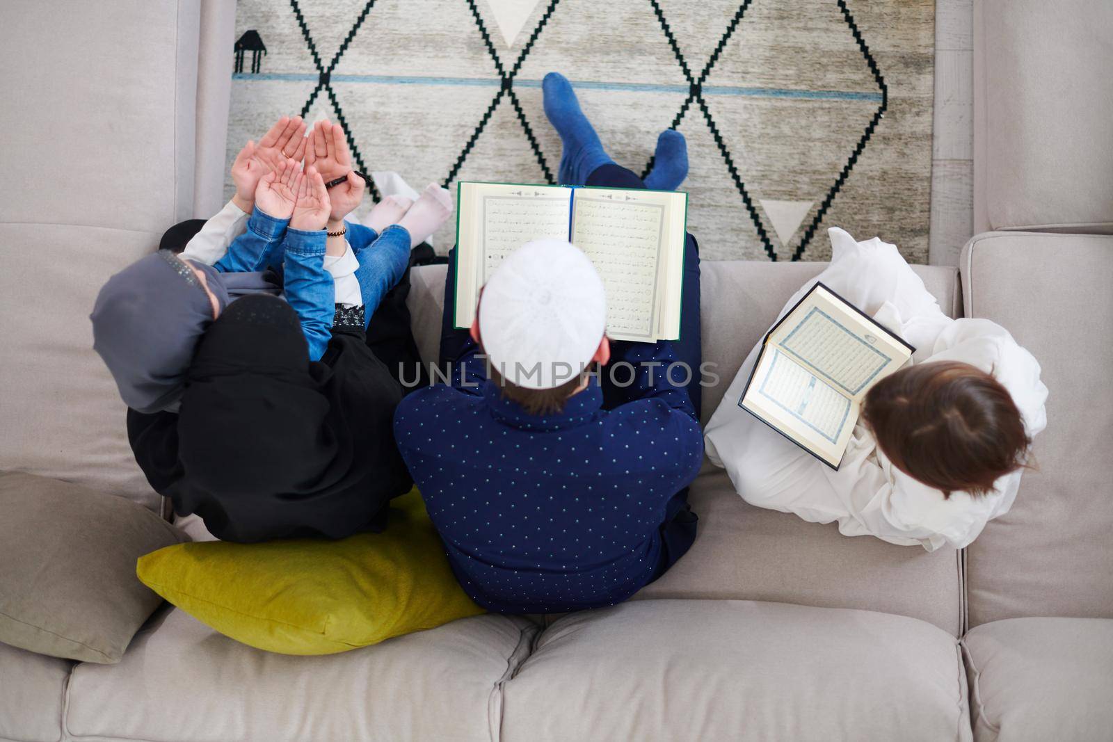 muslim family reading Quran and praying at home top view by dotshock