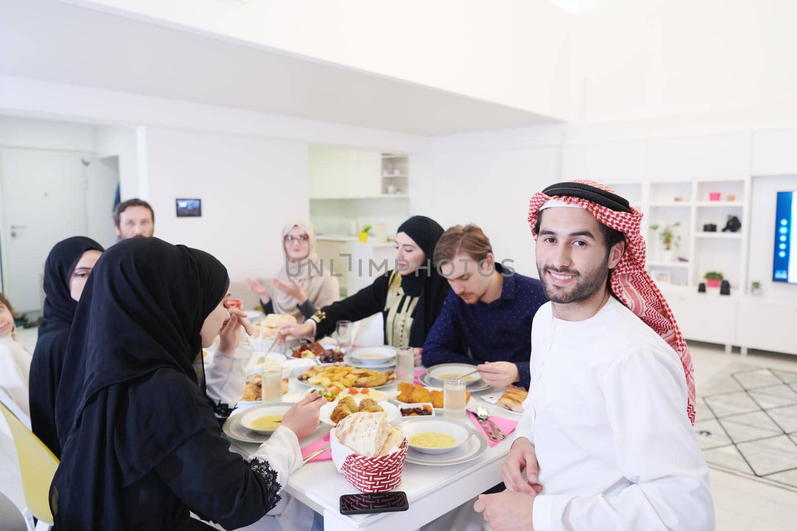 young arabian man having Iftar dinner with muslim family Eating traditional food during Ramadan feasting month at home. The Islamic Halal Eating and Drinking Islamic family