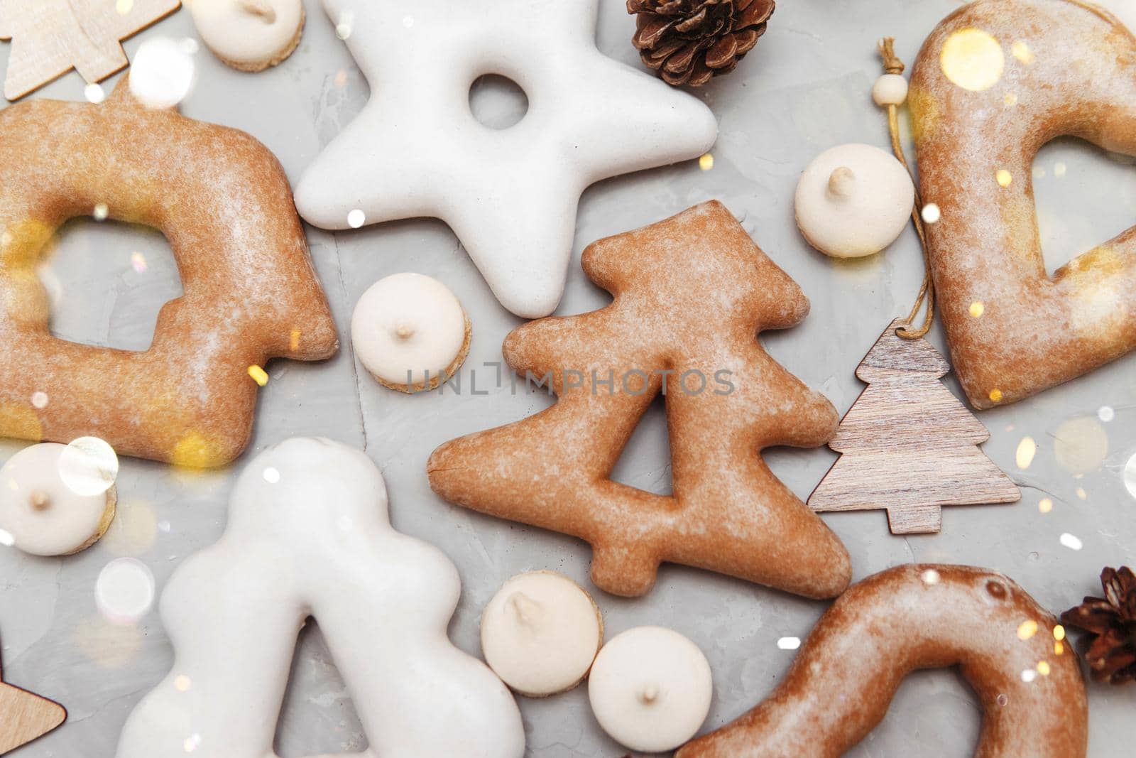 Banner for Christmas and New Year gingerbread stars, houses, Christmas trees, toys on a gray concrete background, Christmas lights bokeh in the foreground.