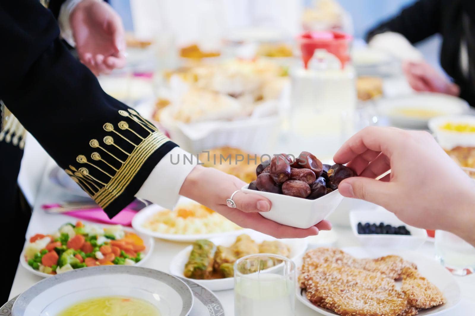 Muslim family having Iftar dinner eating dates to break feast by dotshock