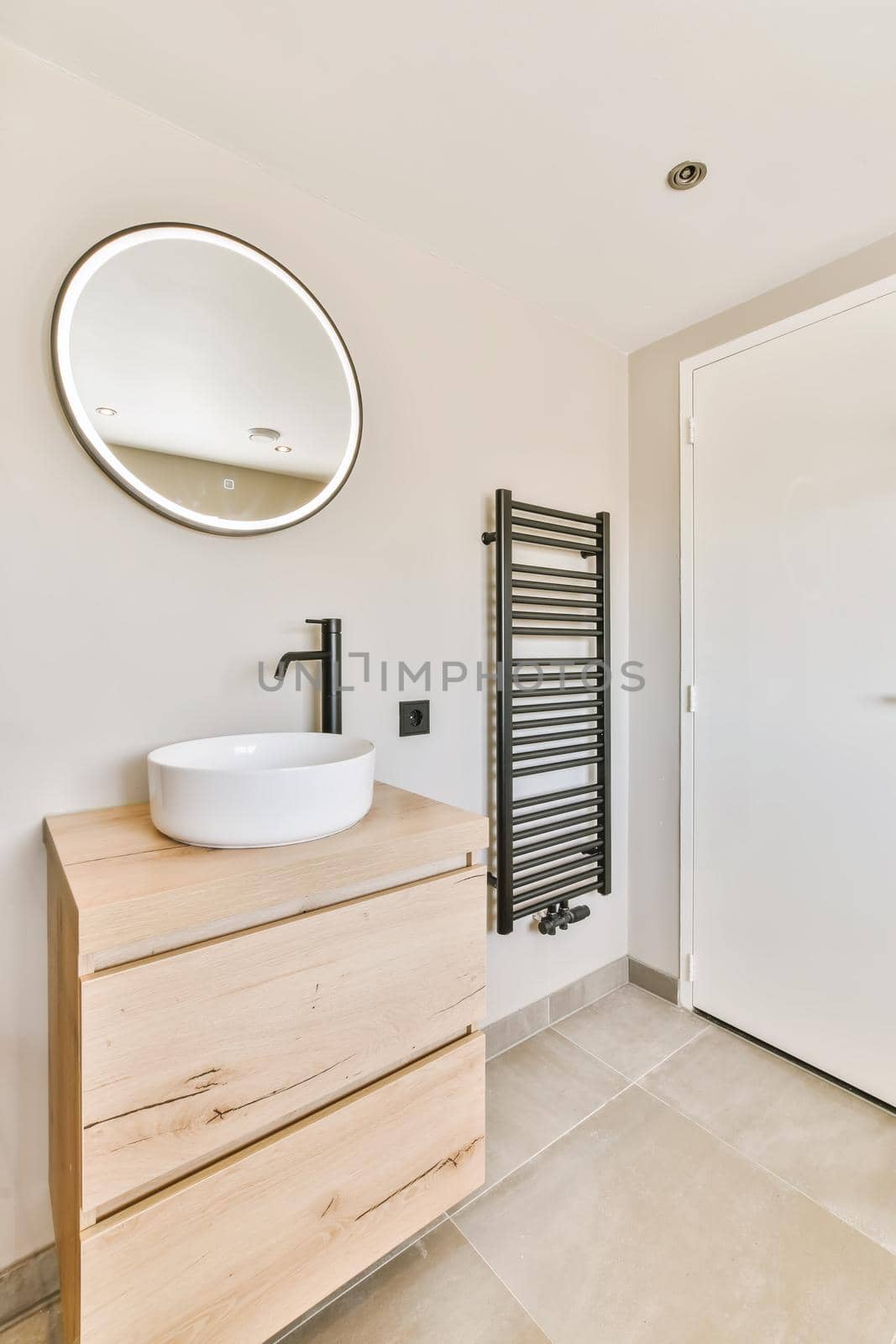 Minimalist bathroom with illuminated round mirror by casamedia