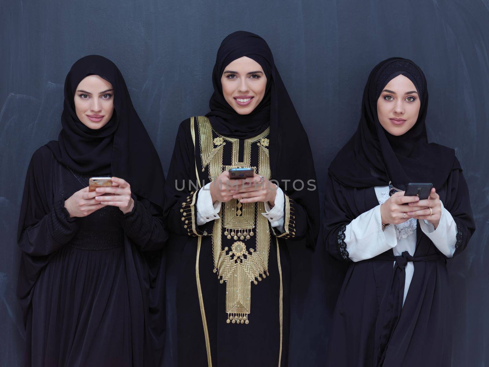 muslim women using mobile phone in front of black chalkboard by dotshock