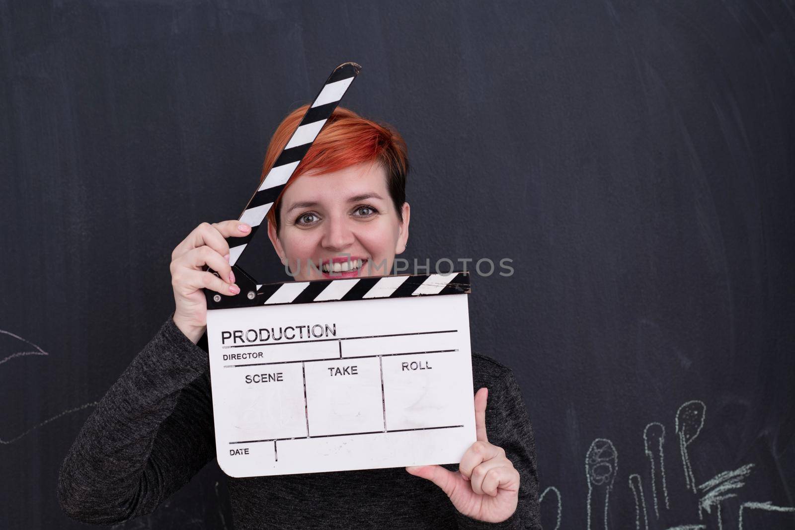 redhead woman holding clapper on black background by dotshock